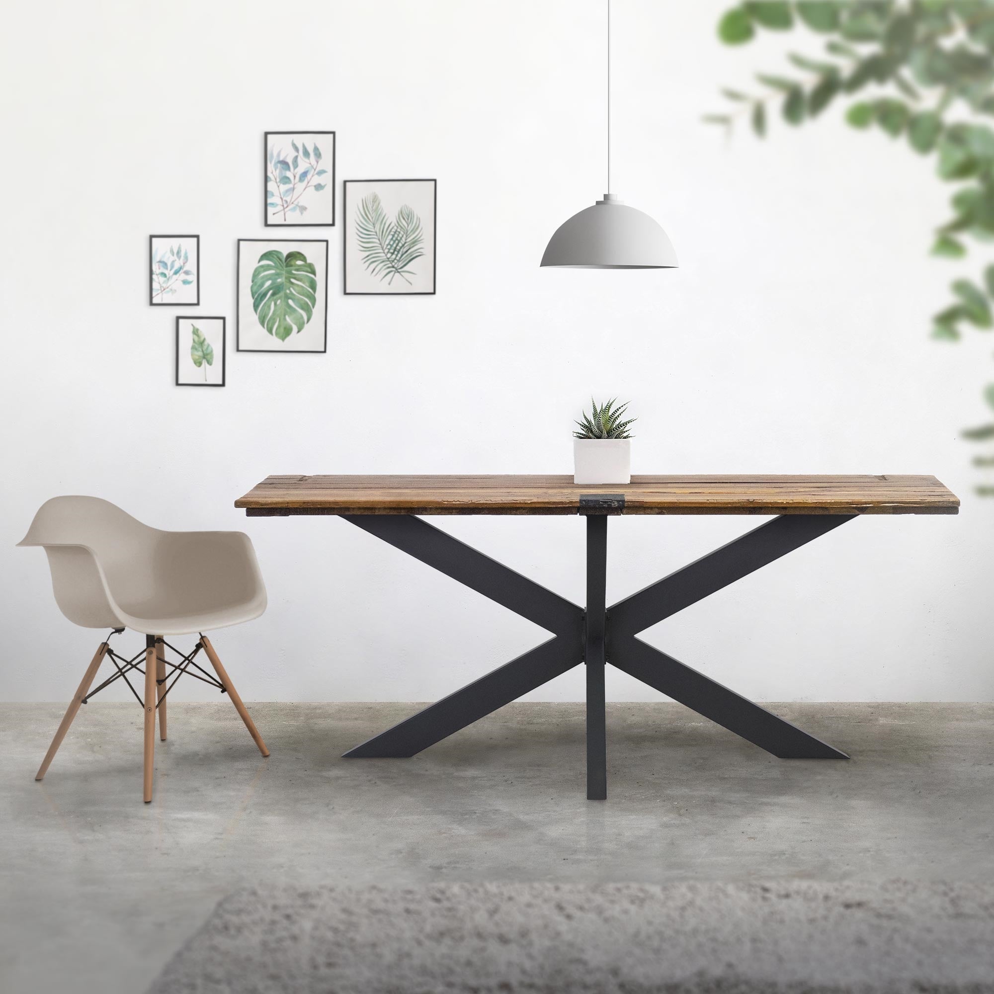 Holztisch mit schwarzem Gestell, Stuhl und Bildern an der Wand.
