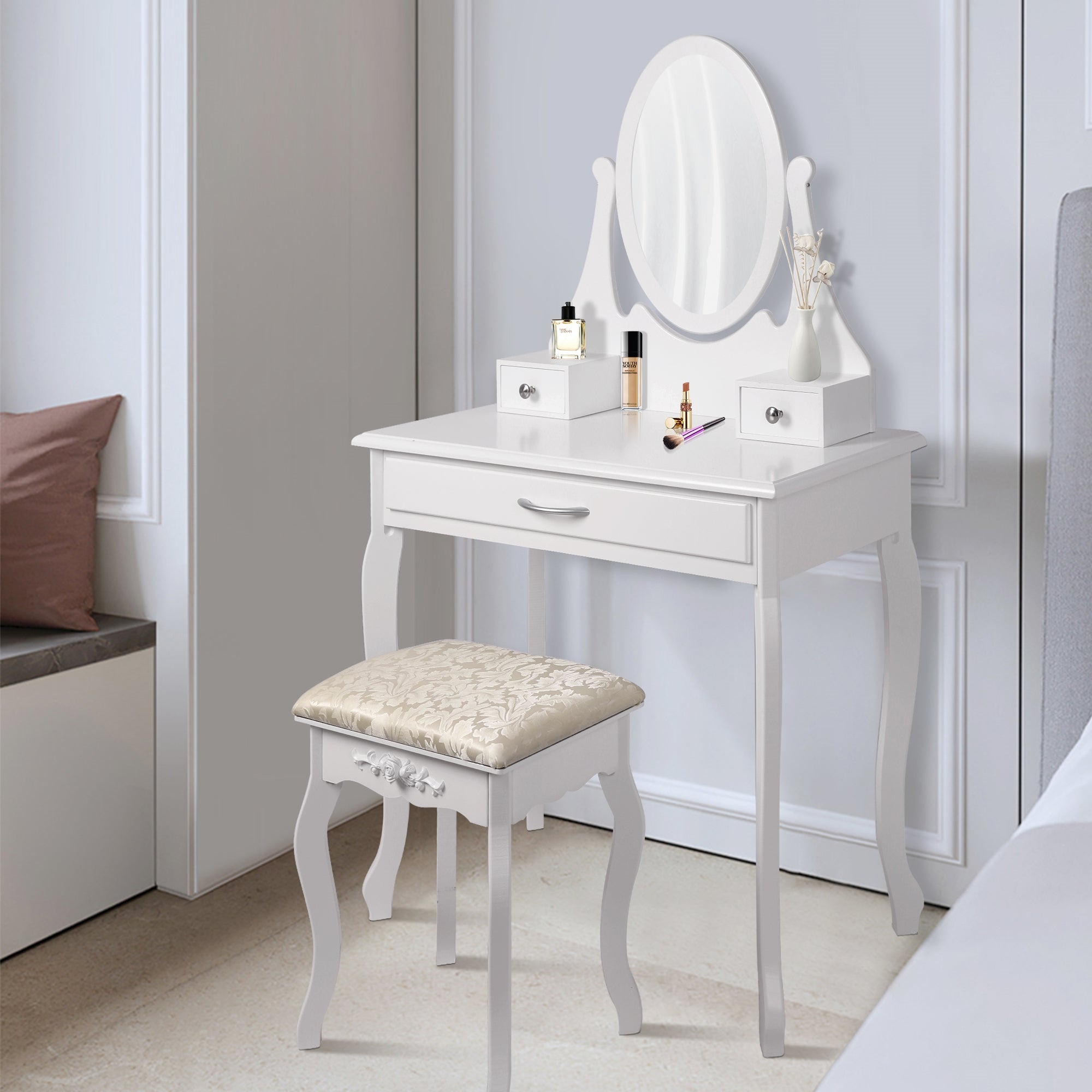 Witte make-up tafel met spiegel, kruk en decoratieve flessen.