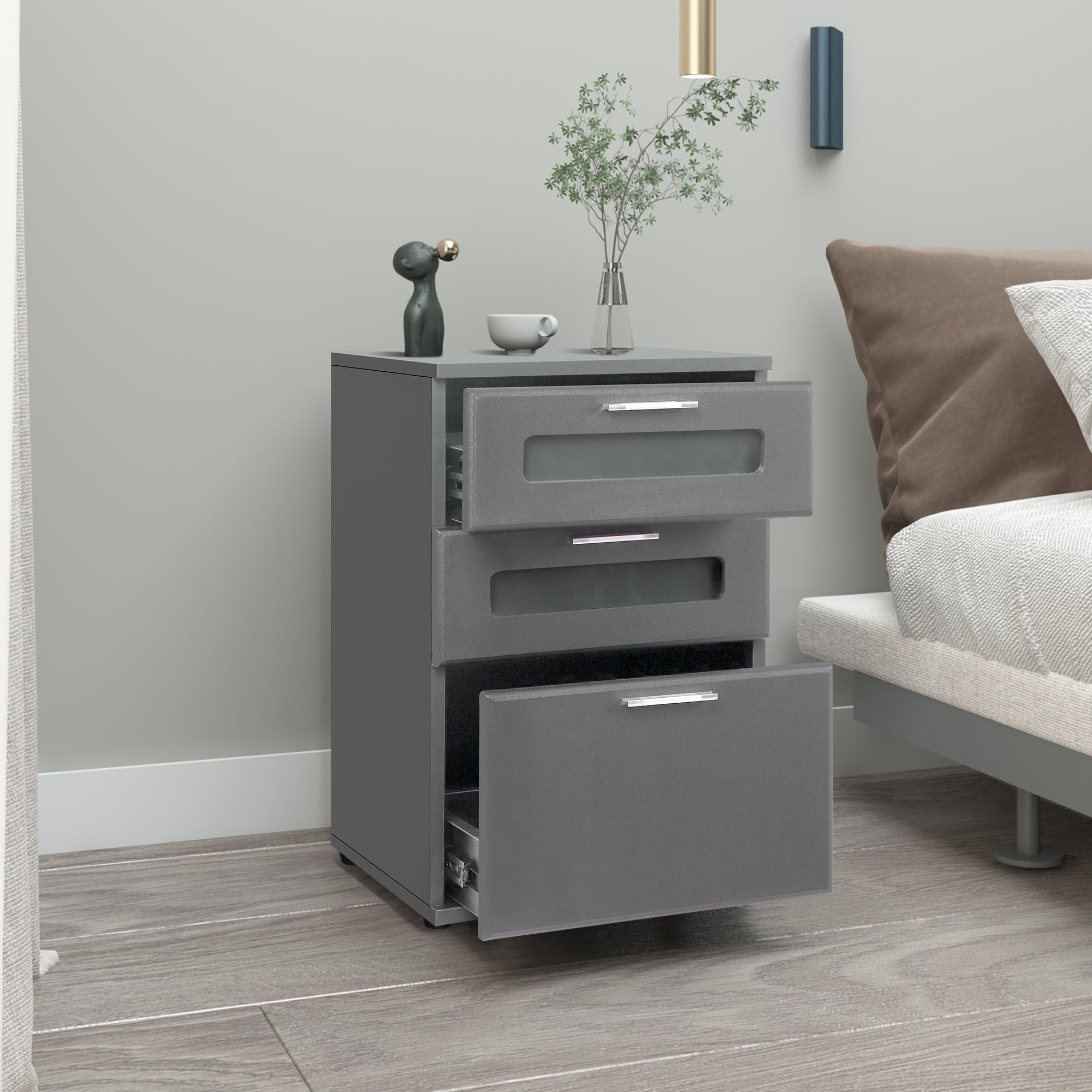 Gray nightstand with three drawers and a plant on the surface.
