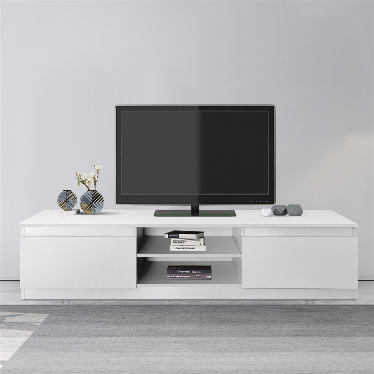 Móvel de TV branco com televisão e objetos decorativos.