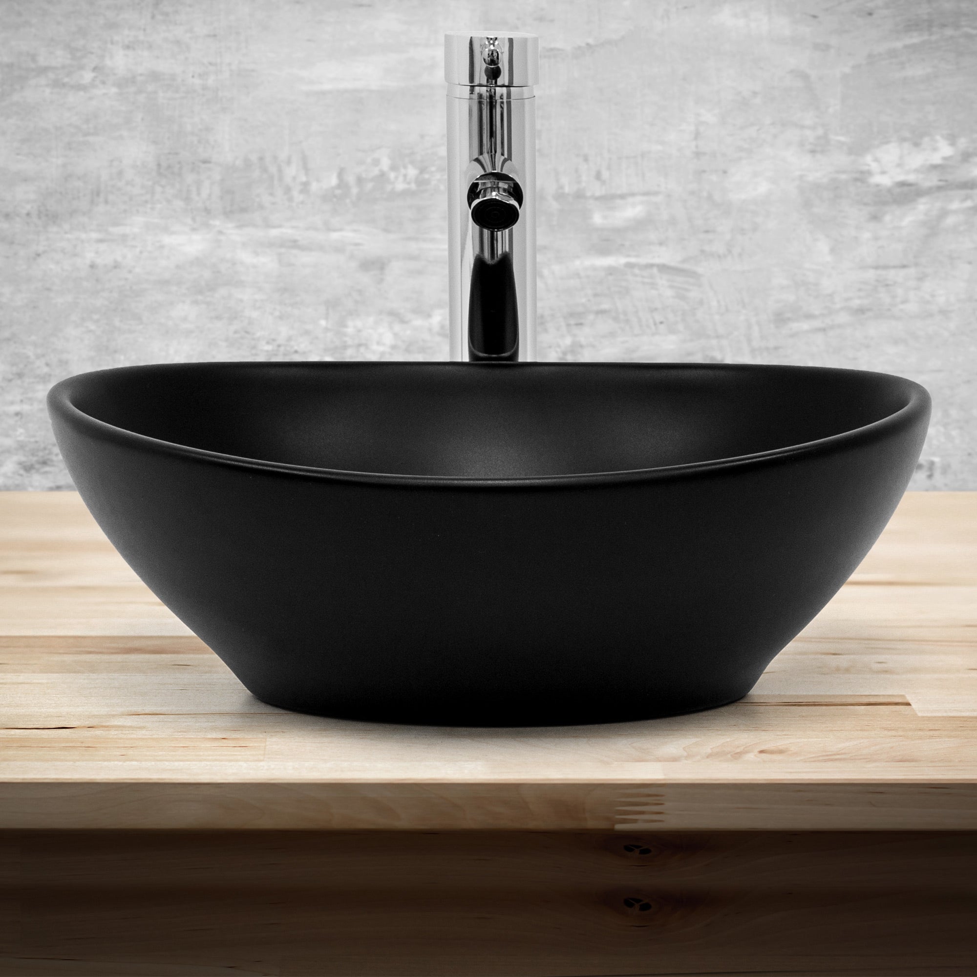 Schwarze, ovale Waschschüssel auf Holzoberfläche, mit Wasserhahn.