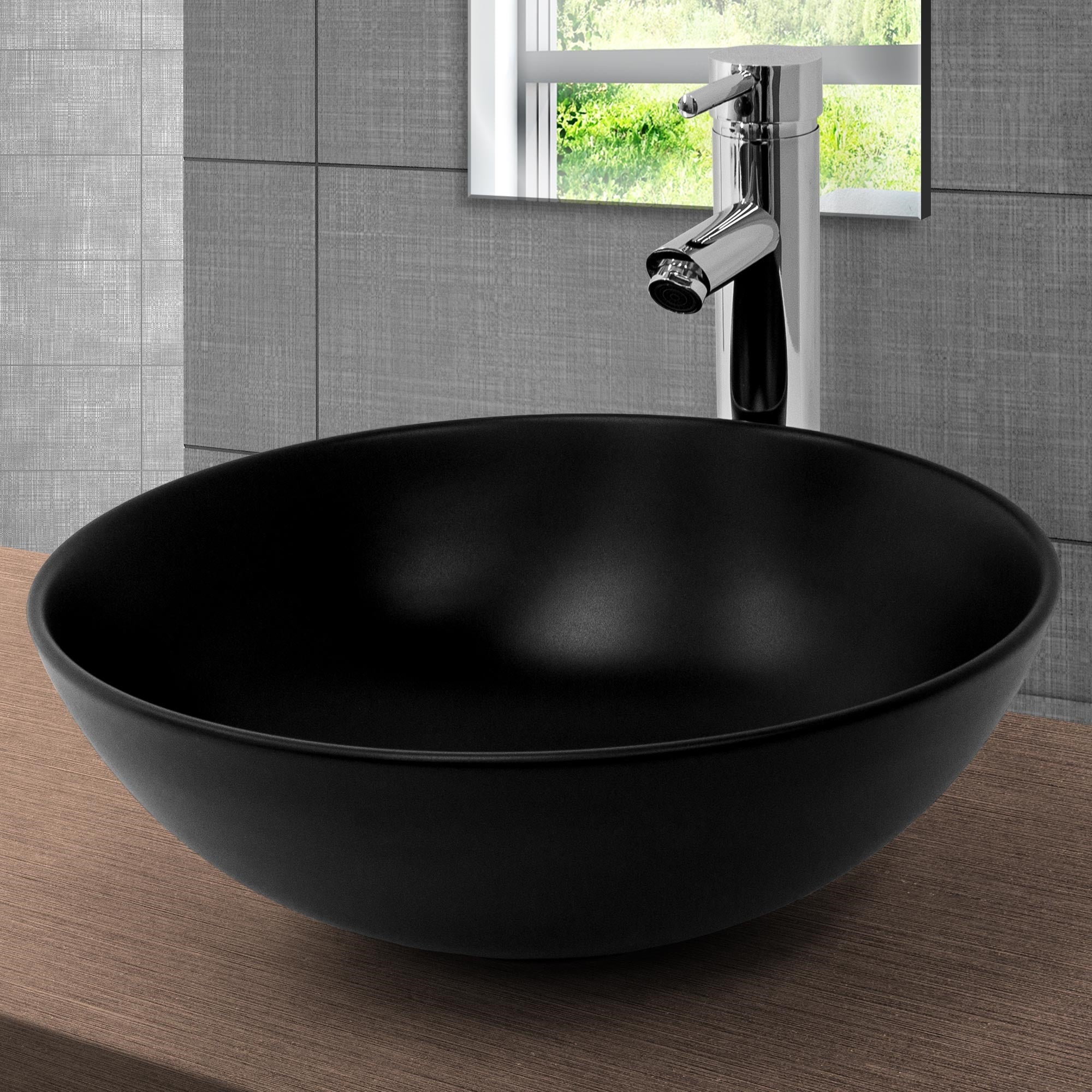 Cuenco de lavabo negro y redondo sobre una superficie de madera con grifo al fondo.
