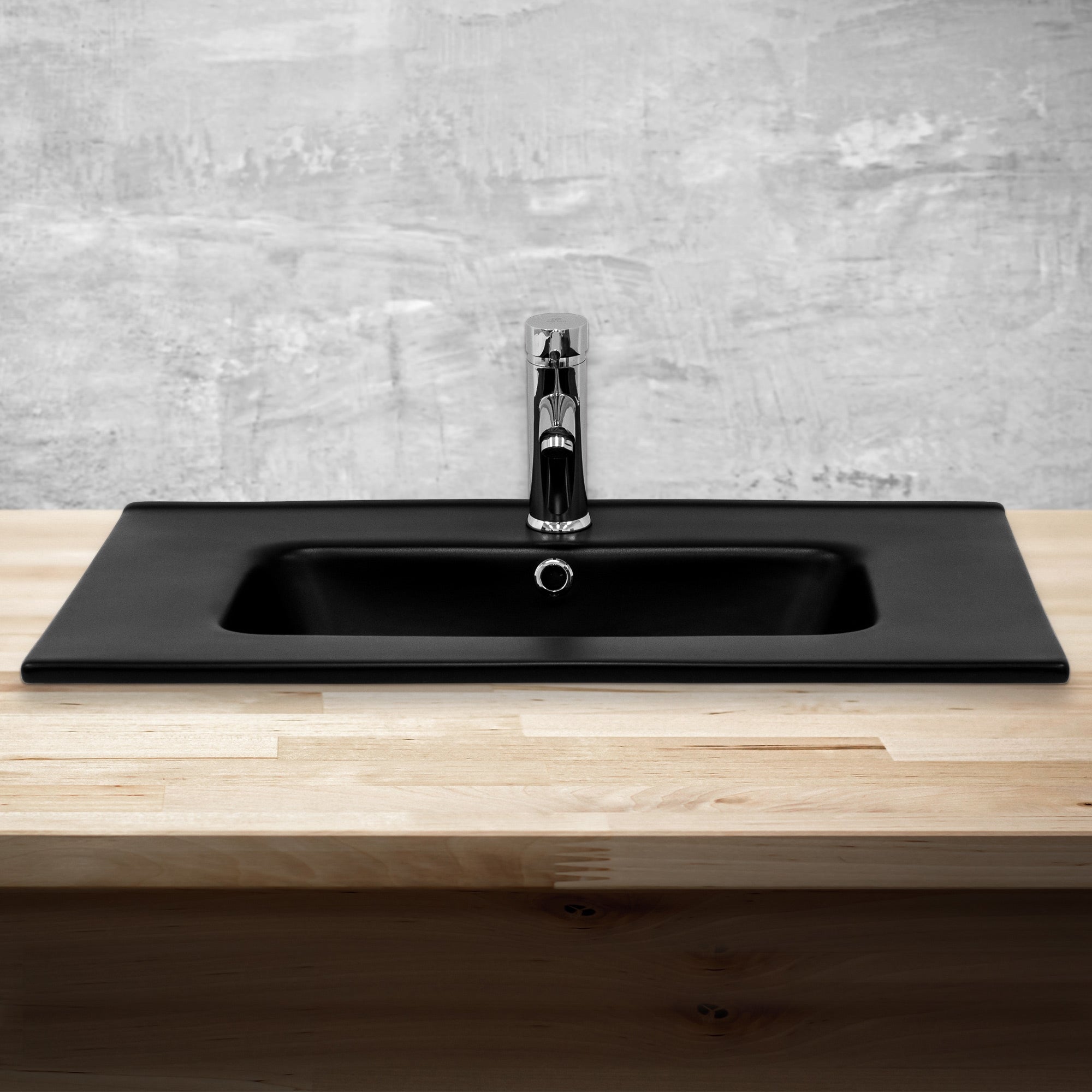 Schwarzes Waschbecken mit Wasserhahn auf einer Holzoberfläche.