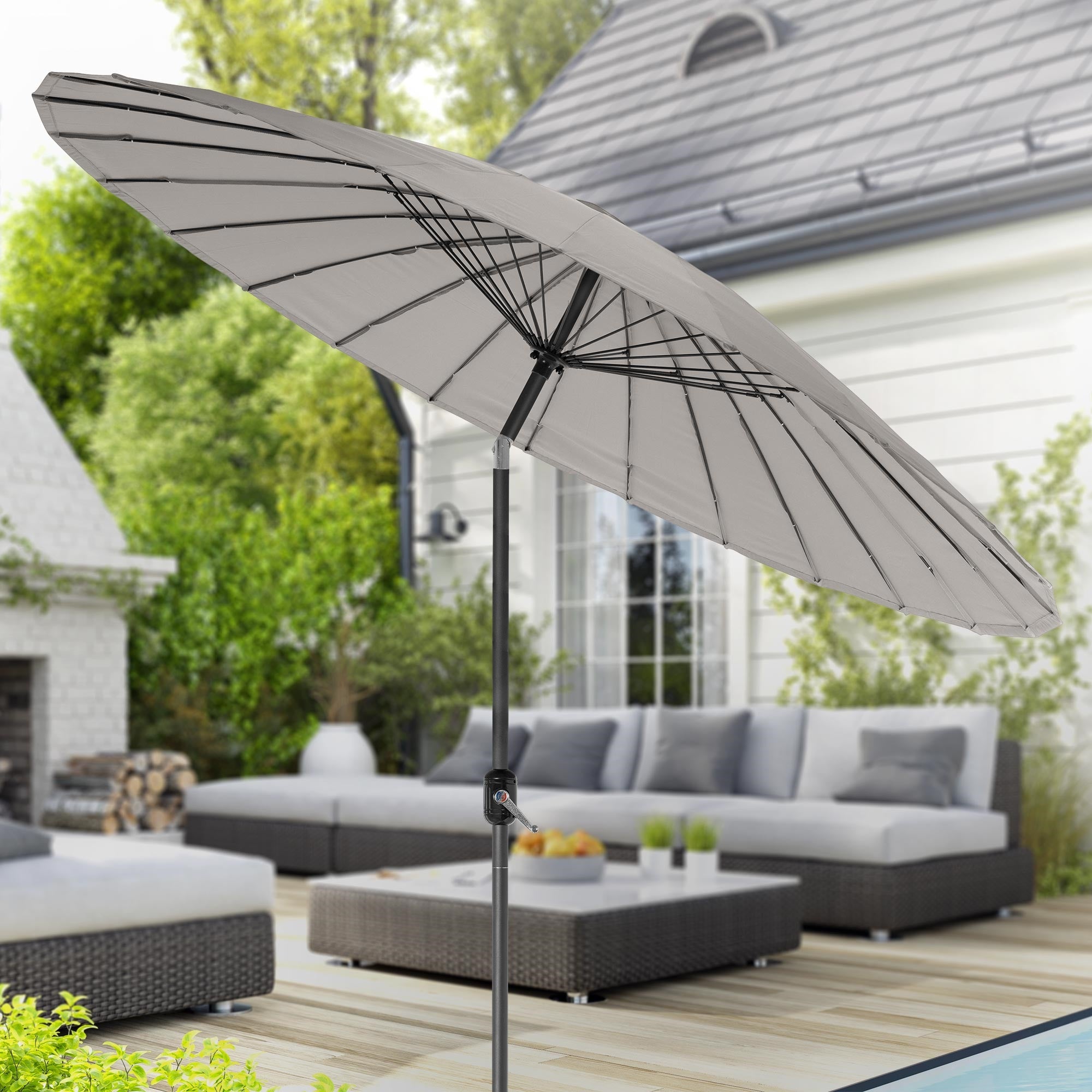Geopende parasol op een terras met zitmeubelen op de achtergrond.