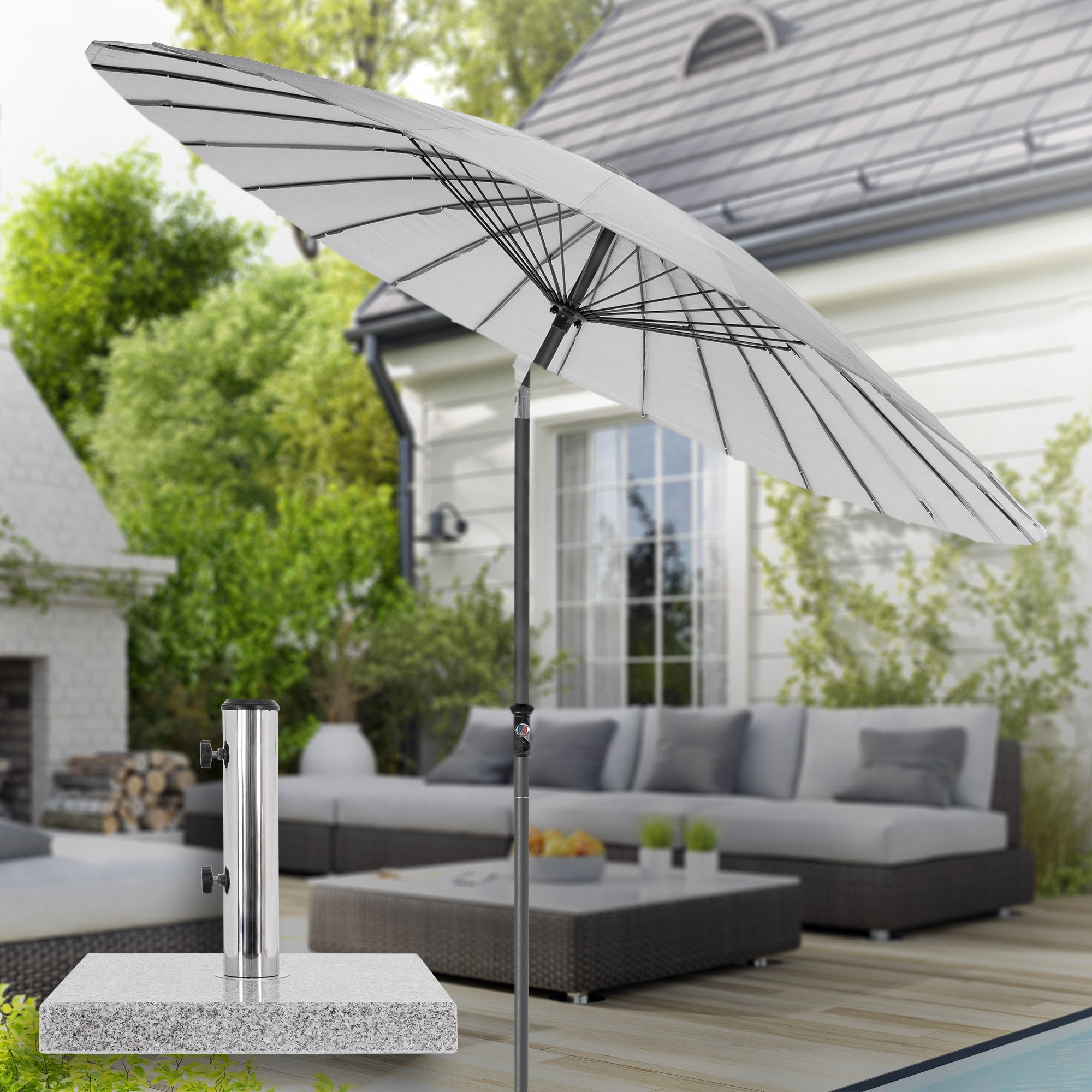 Garten mit einem großen Sonnenschirm und einer Lounge-Ecke aus Rattan.
