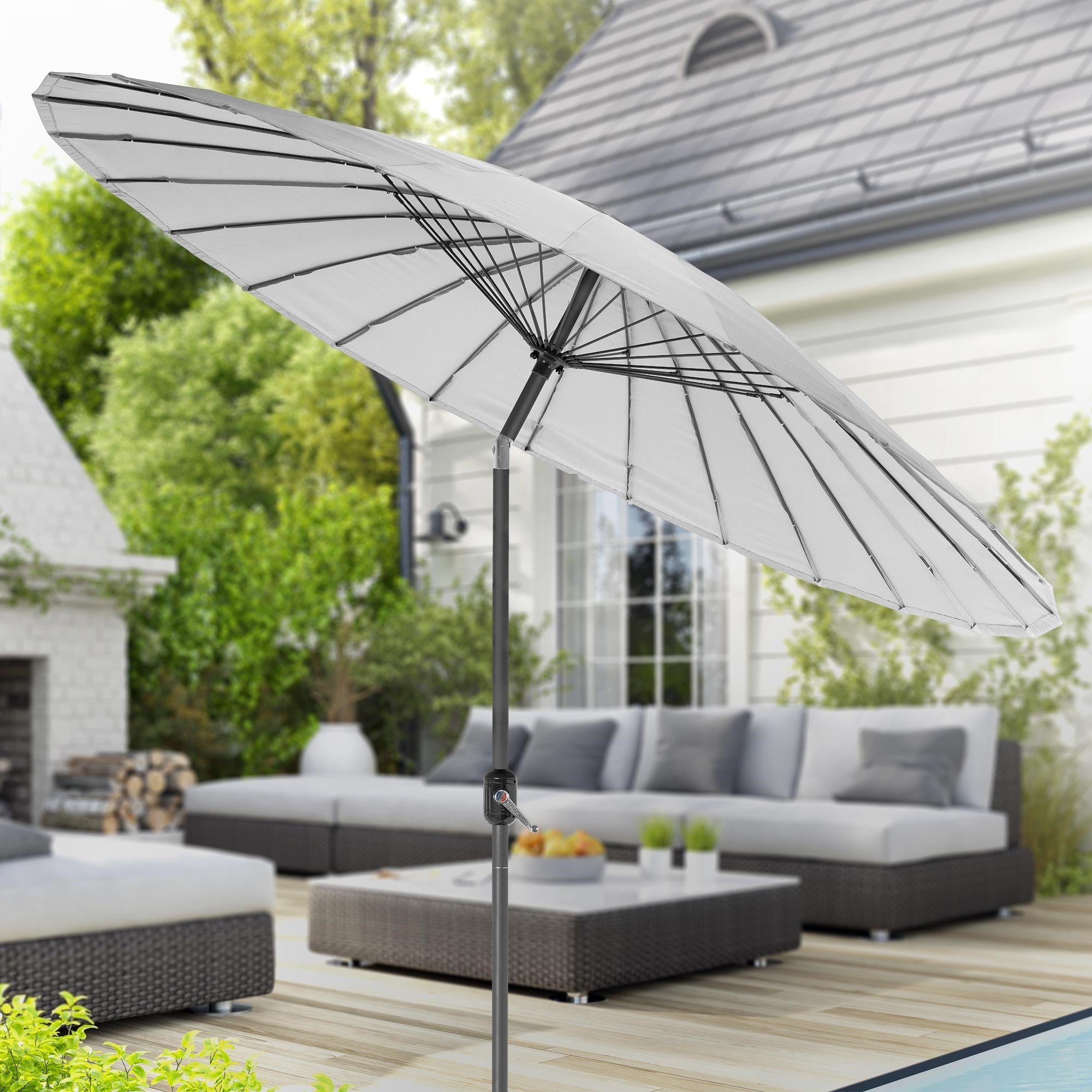 Parasol gris clair sur une terrasse avec des meubles de jardin en arrière-plan.