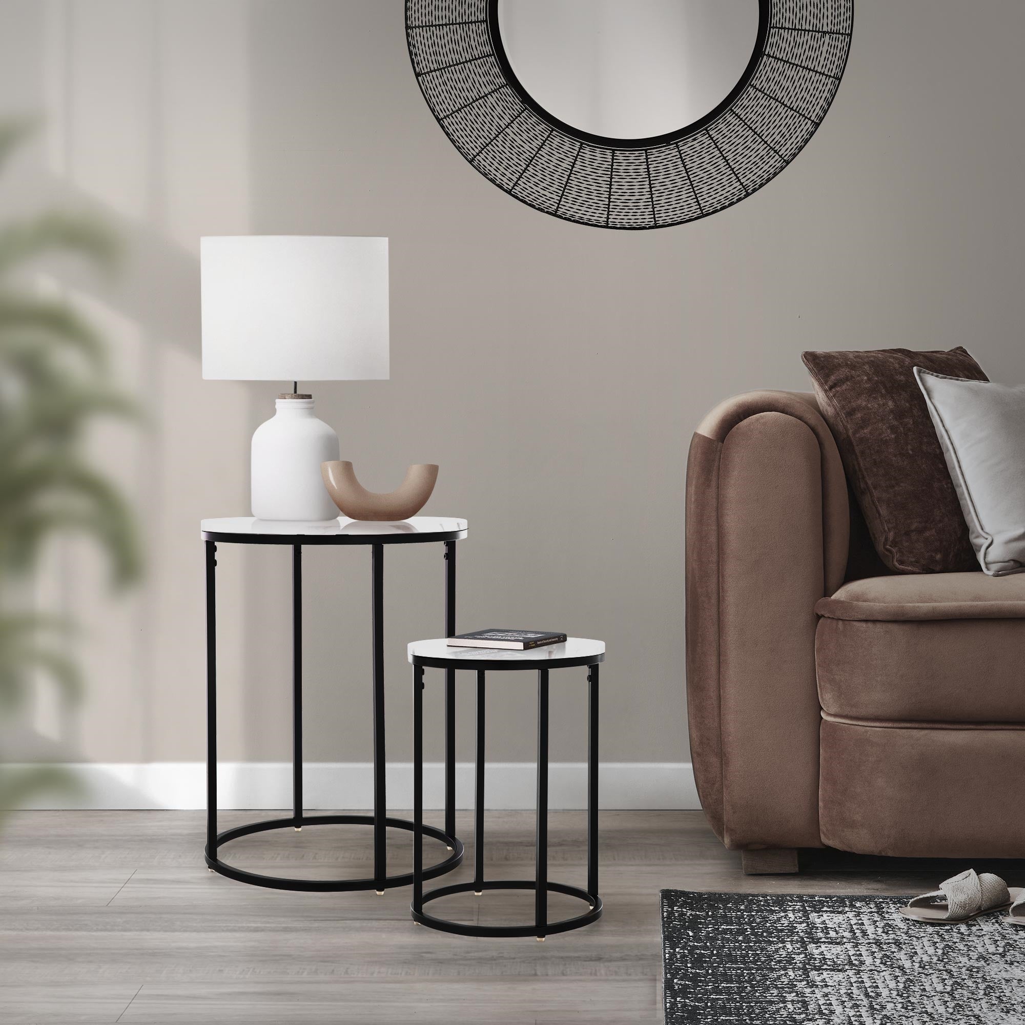 Wohnzimmer mit zwei Beistelltischen, Lampe und runder Wandspiegel.