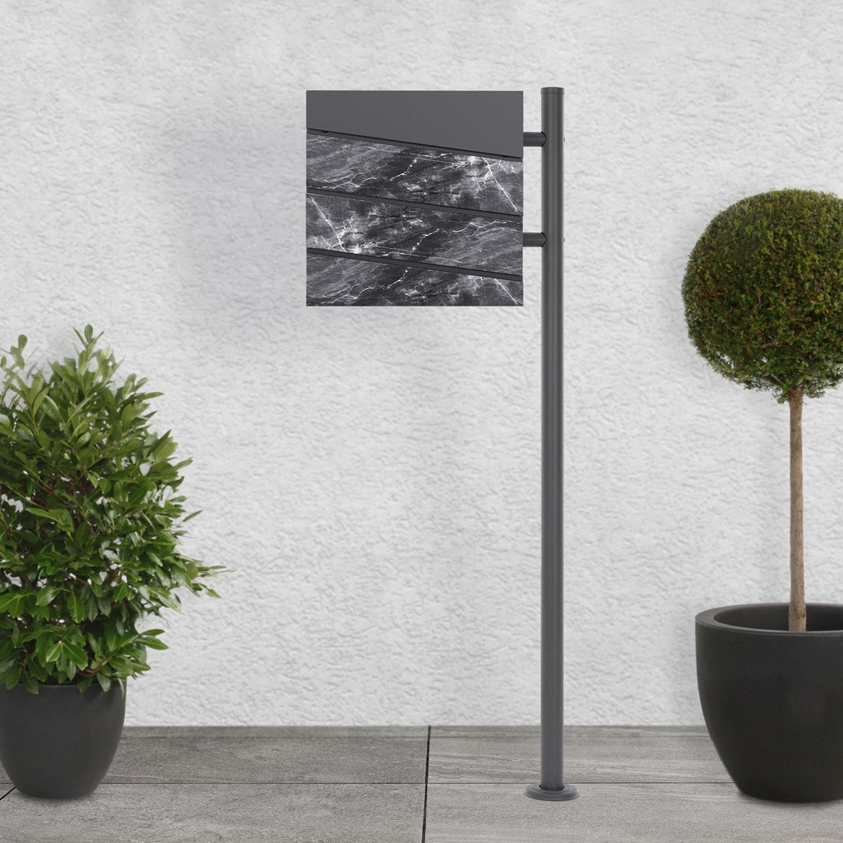 Moderne brievenbusinstallatie met een grijs ontwerp en planten op de voorgrond.