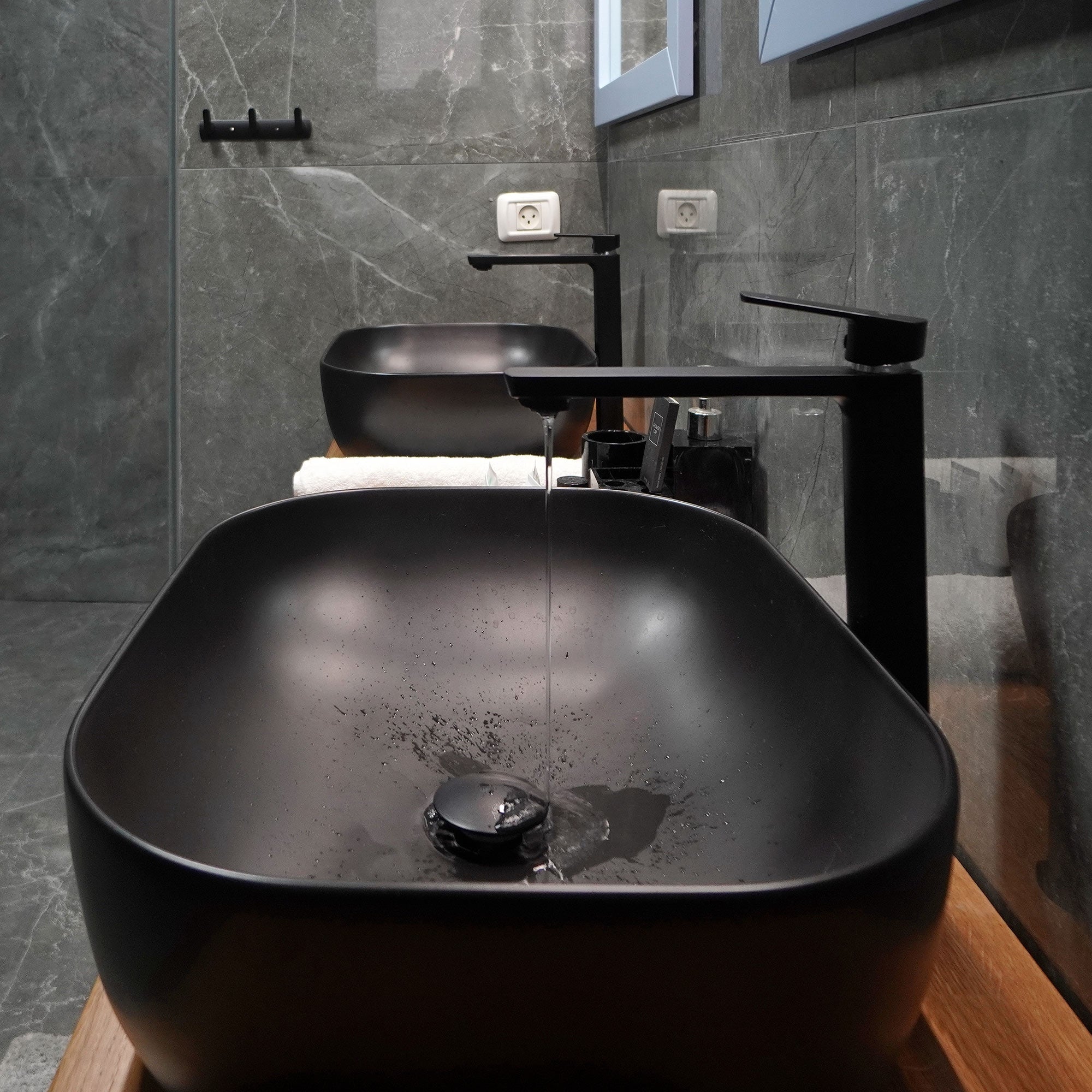 Two black sinks with a faucet in a modern bathroom.