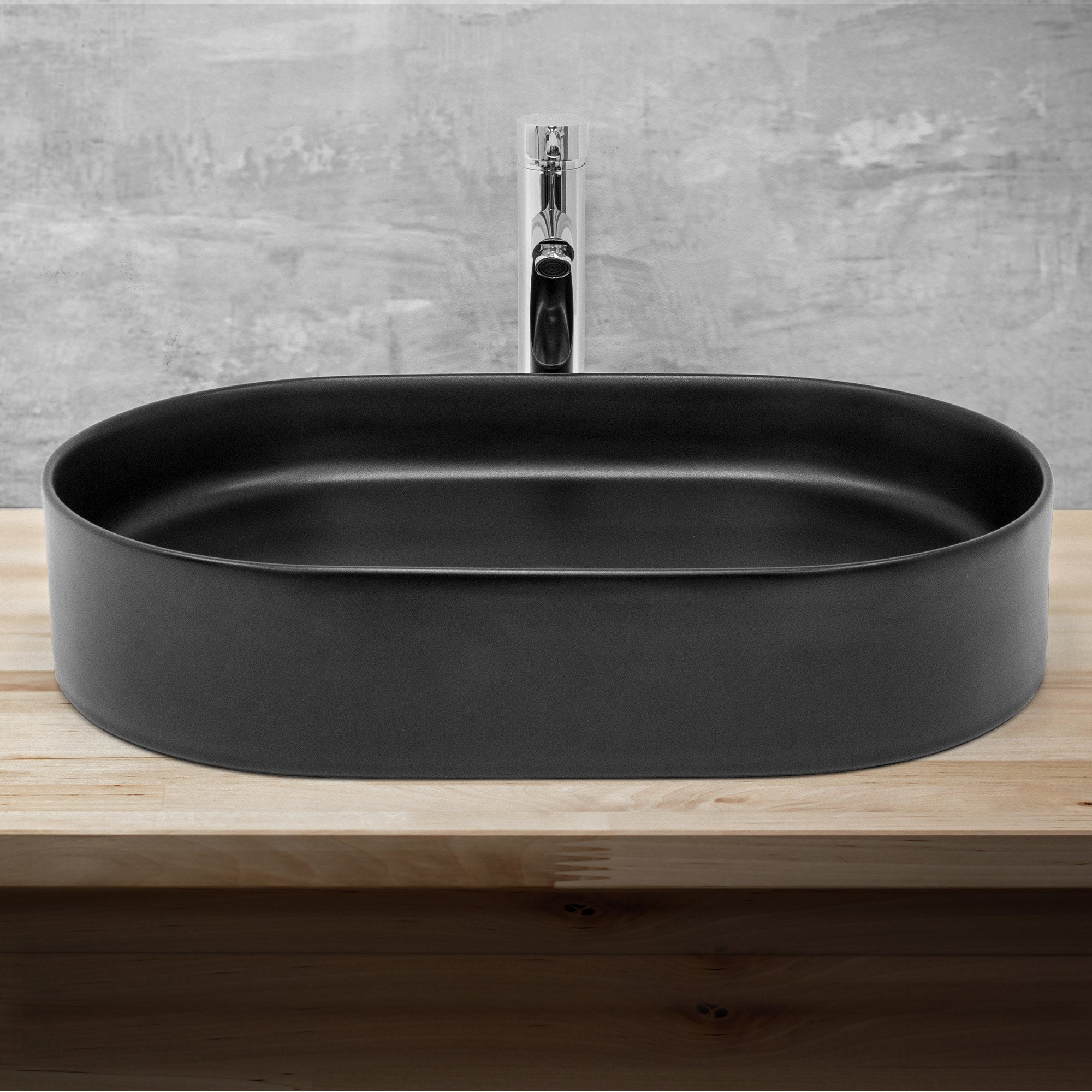 Black, oval sink on a wooden surface with faucet.