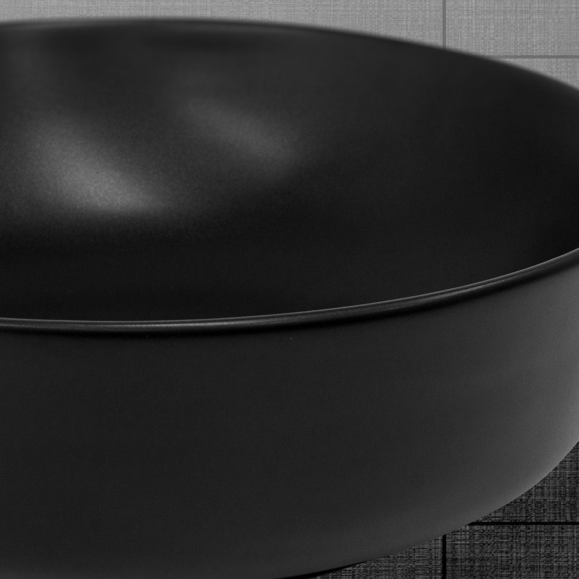 Black round bowl on a gray background, close-up.