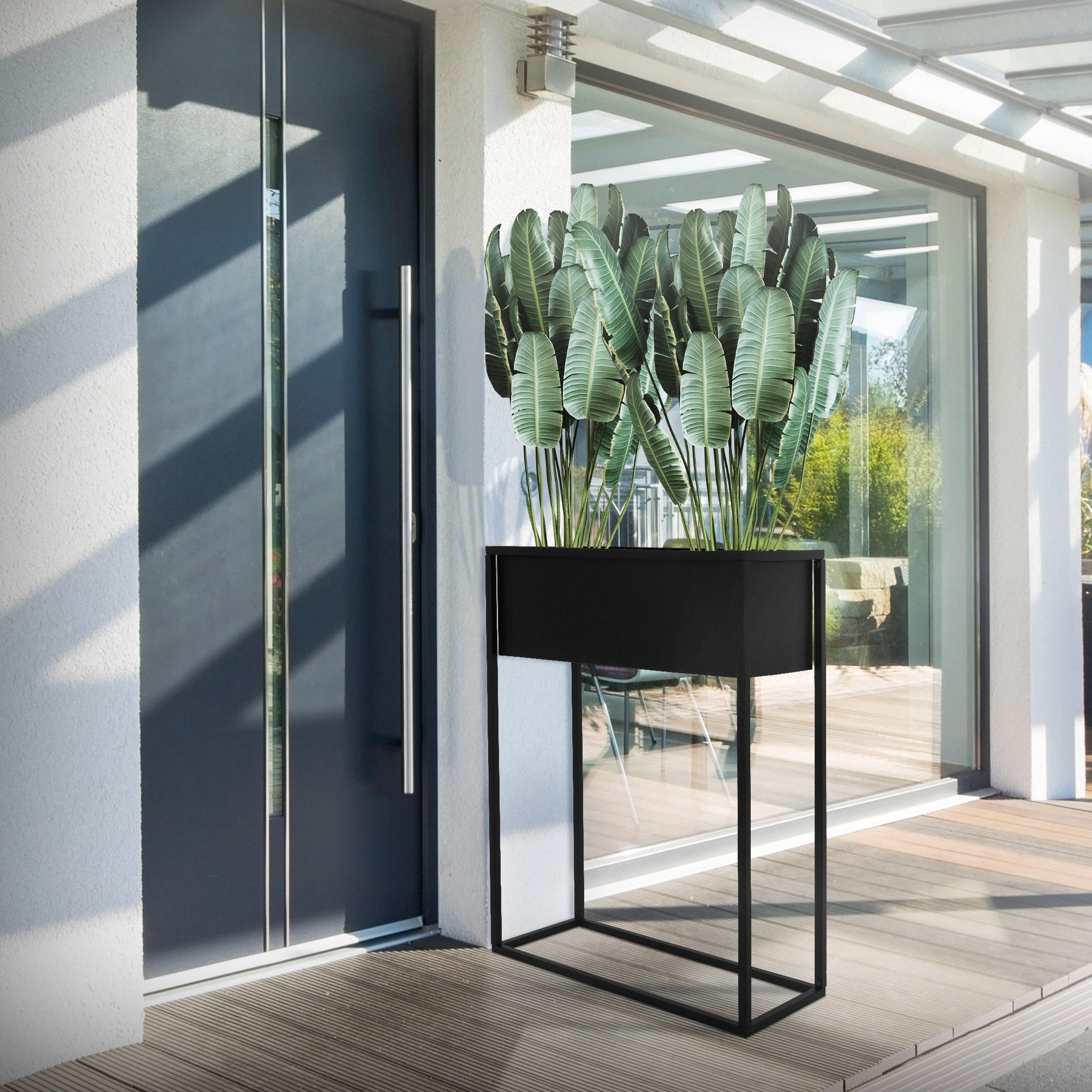 Table de plantation noire avec des plantes devant une porte d'entrée moderne.