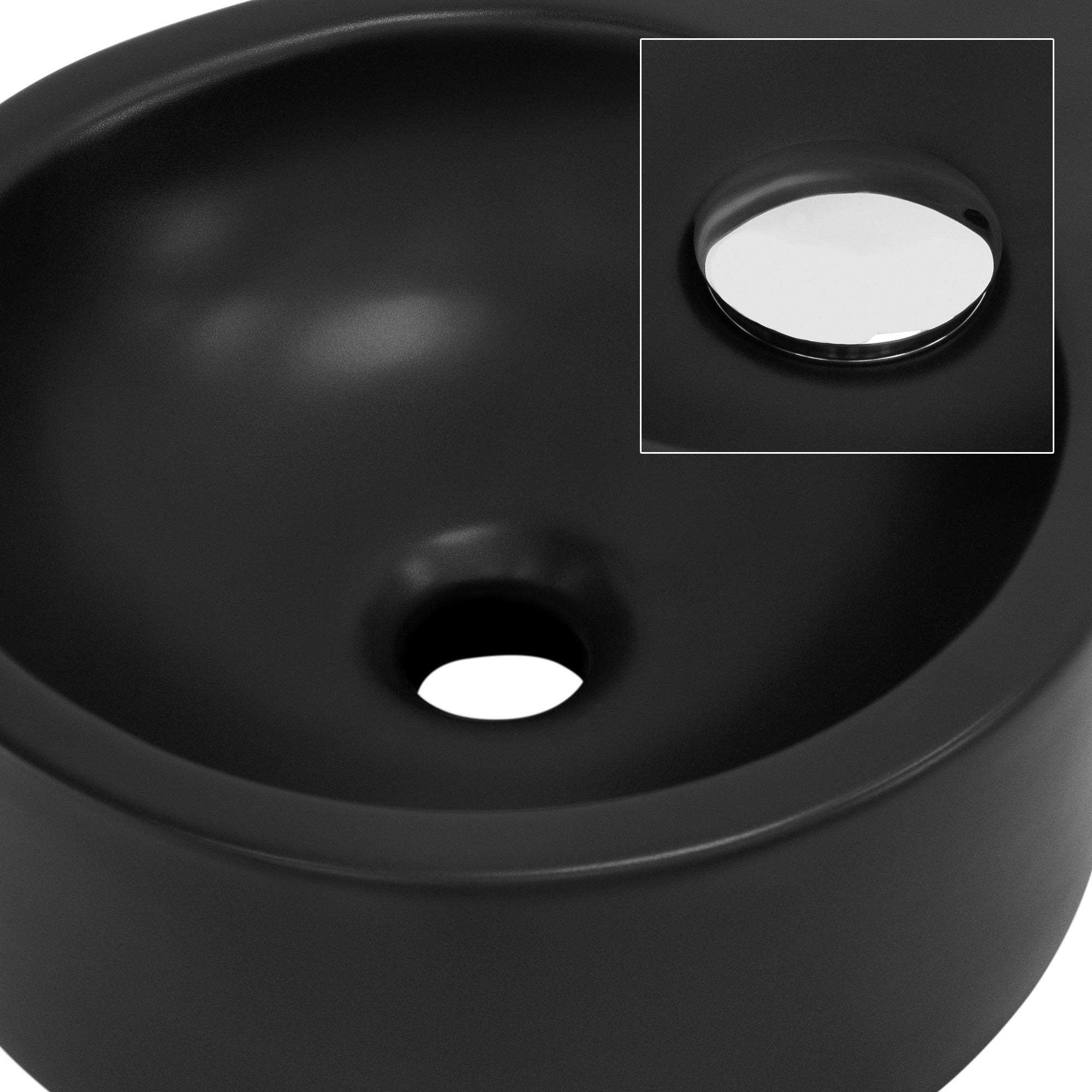 Schwarzes Waschbecken mit Abflussöffnung und Spiegel im Hintergrund.