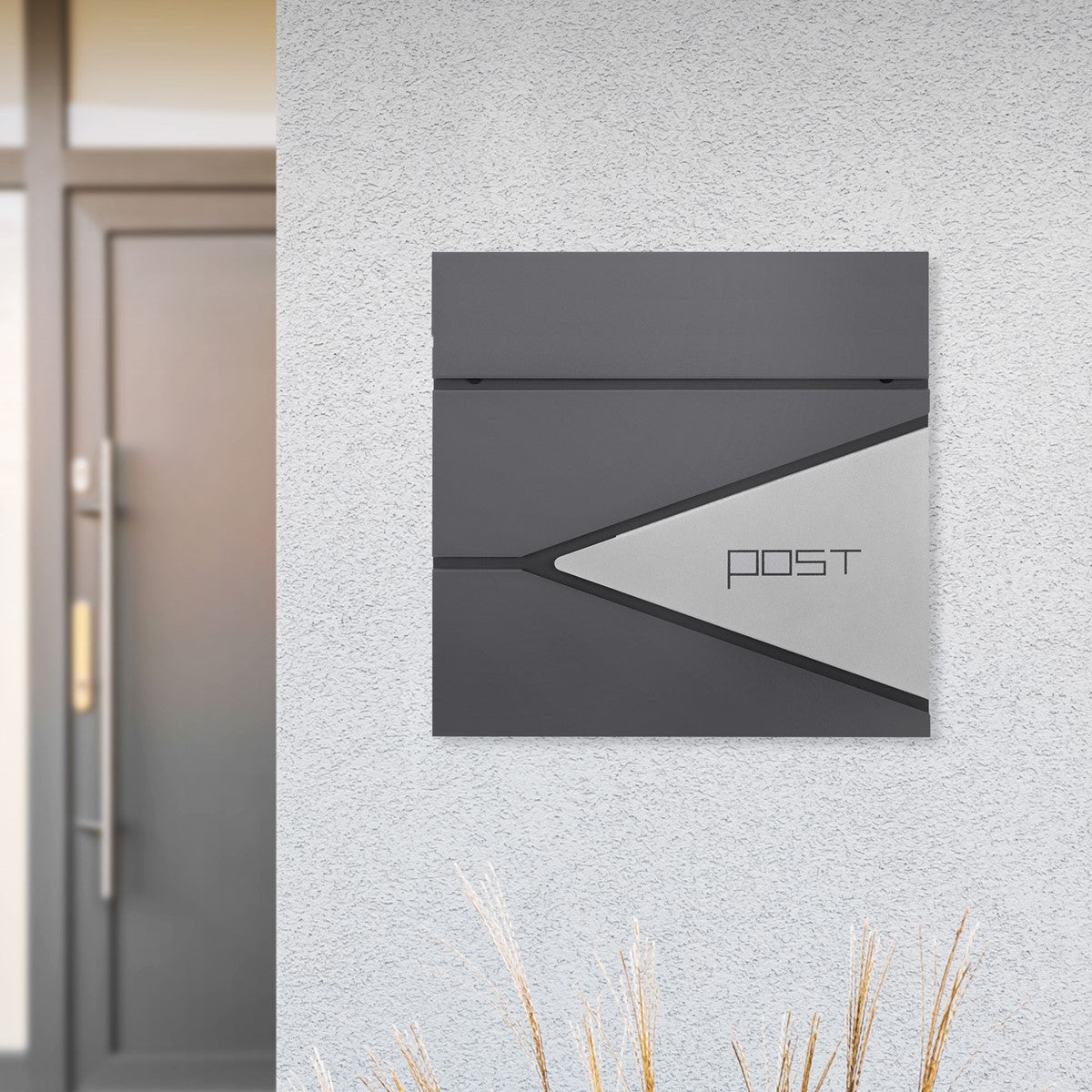 Letterbox on a wall, grey with a silver front, against a light background.