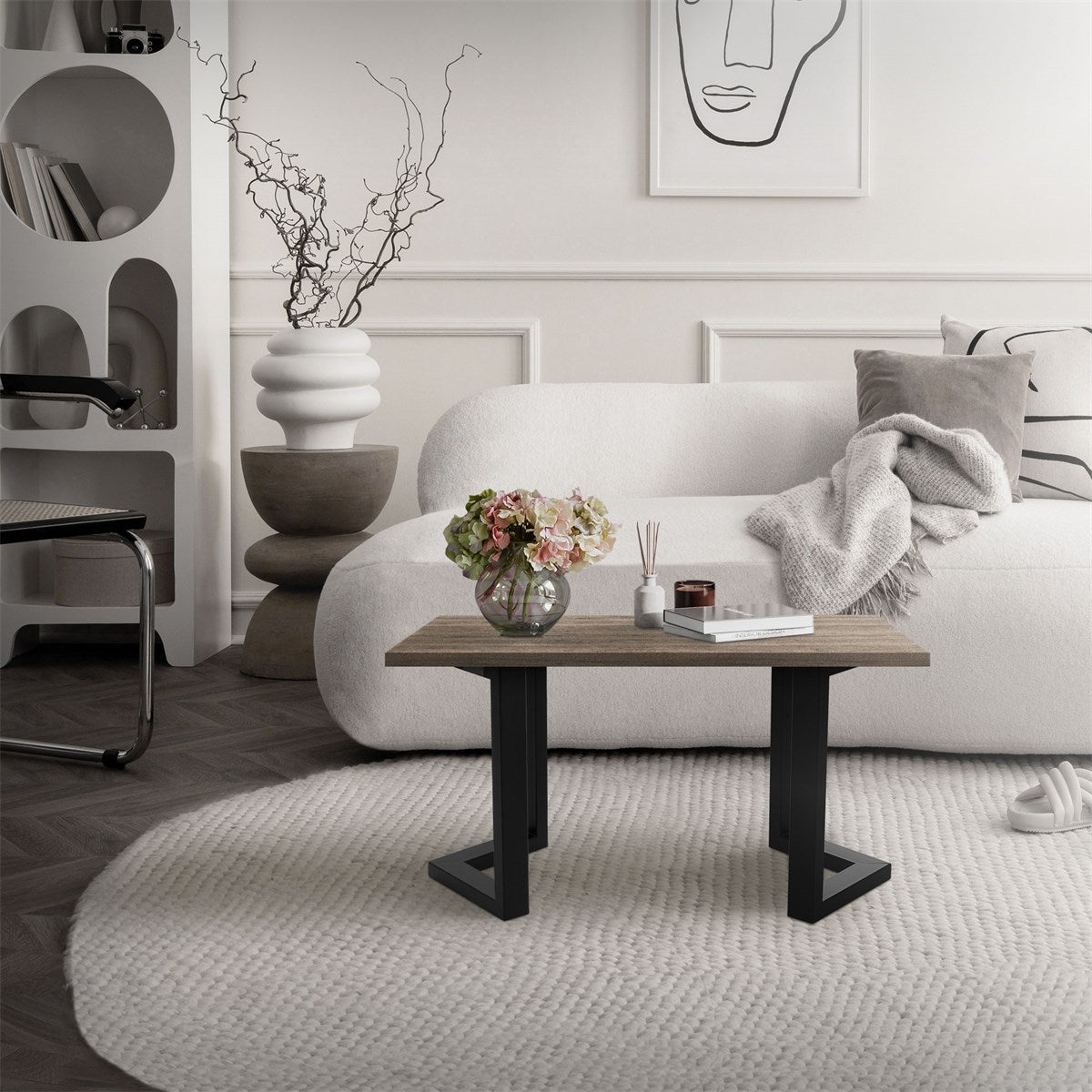 A modern living room with a white sofa, a wooden table and a vase of flowers.