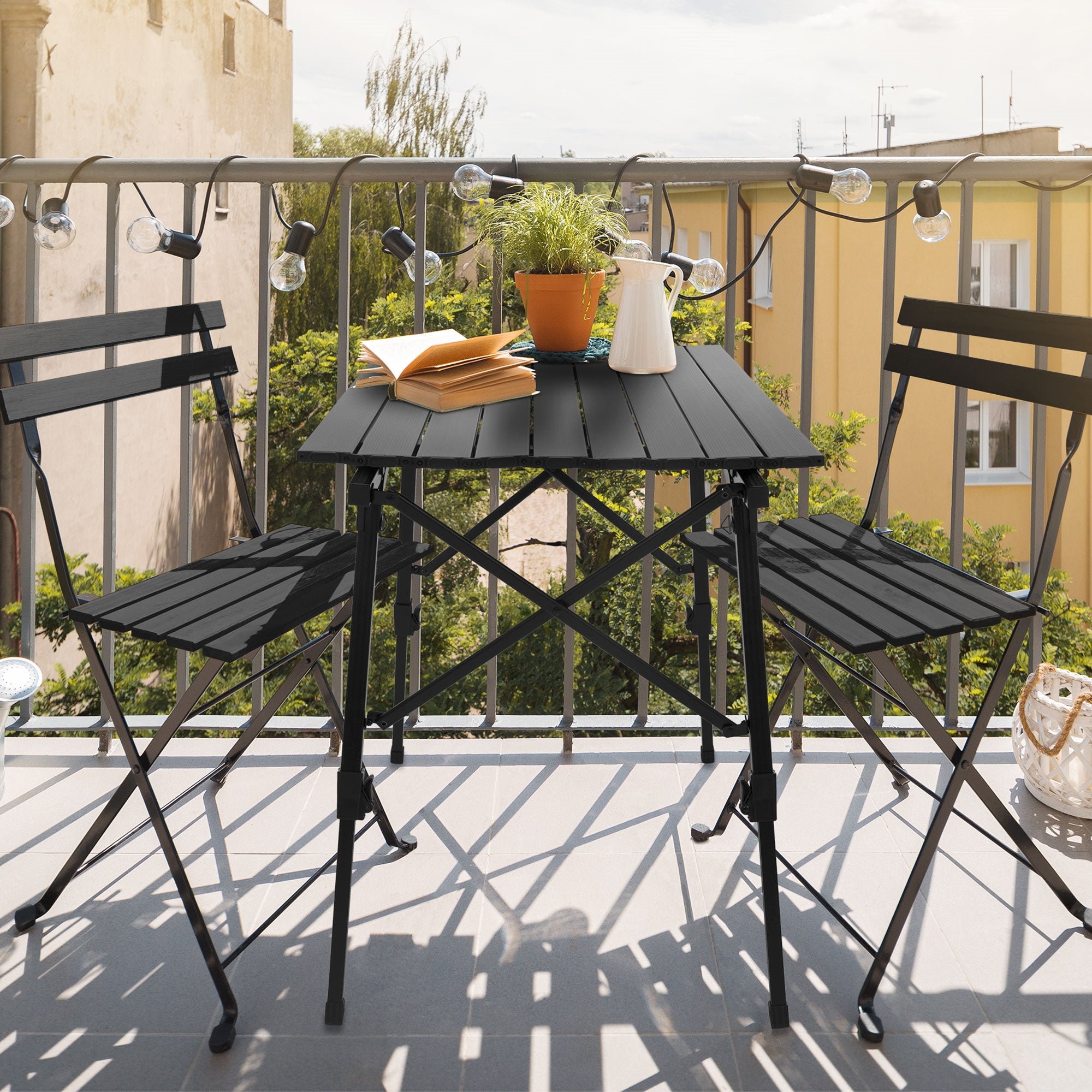 Petite table sur un balcon avec des plantes et un livre.