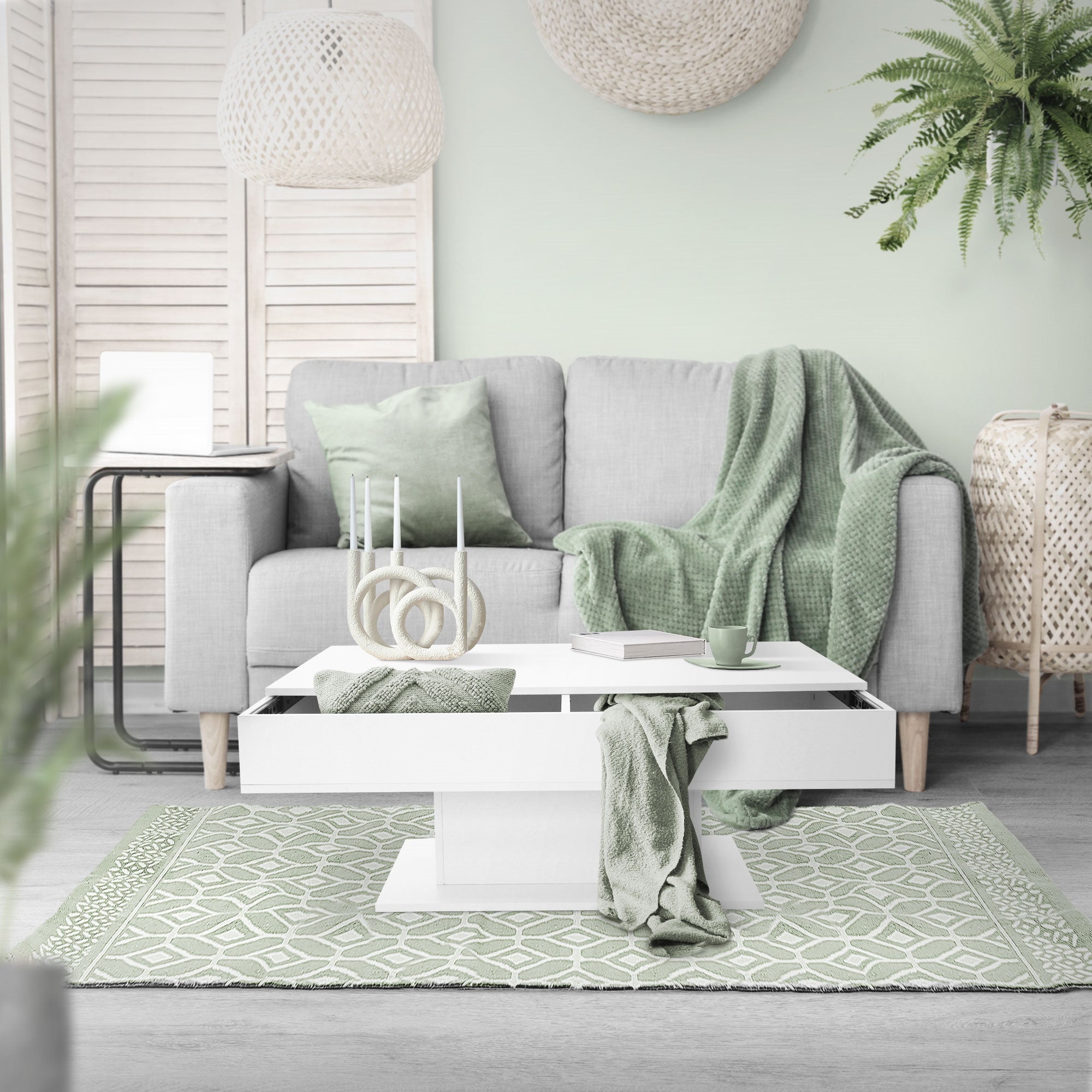 White coffee table with blankets and a cup on a green carpet.