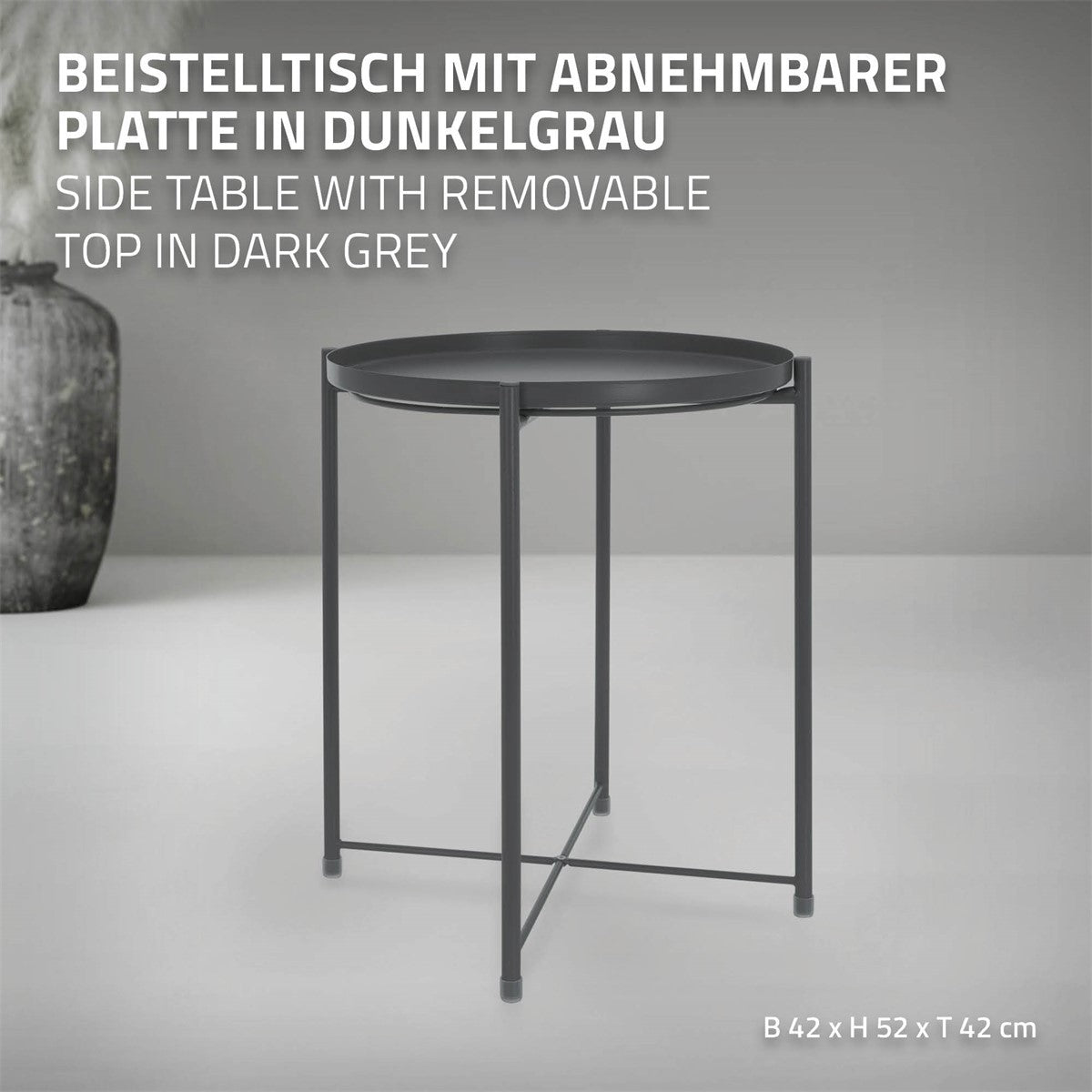 Mesa auxiliar gris oscuro con tablero redondo extraíble, sobre cuatro patas.