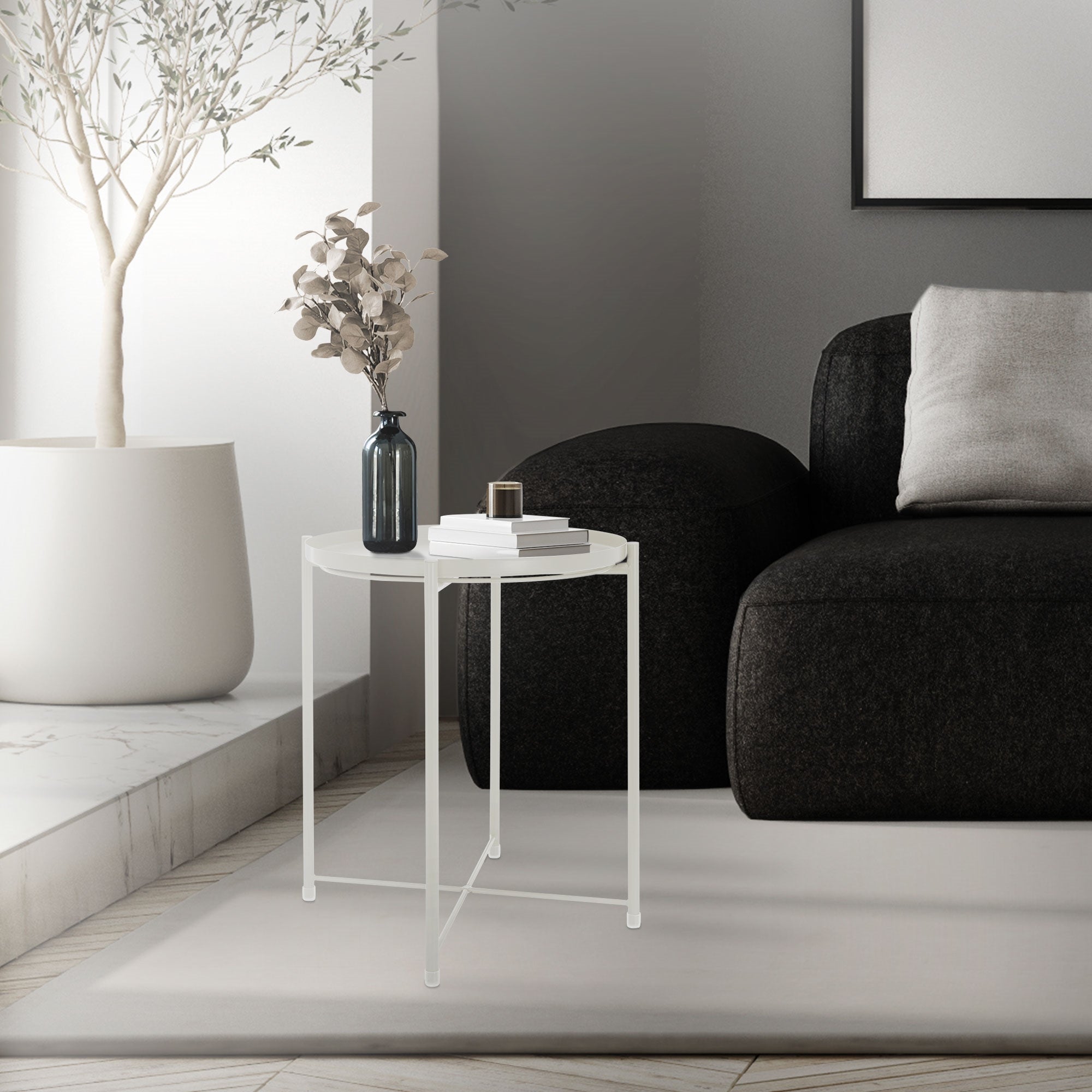 Ein kleiner, transparenter Tisch neben einem schwarzen Sofa in einem hellen Raum.