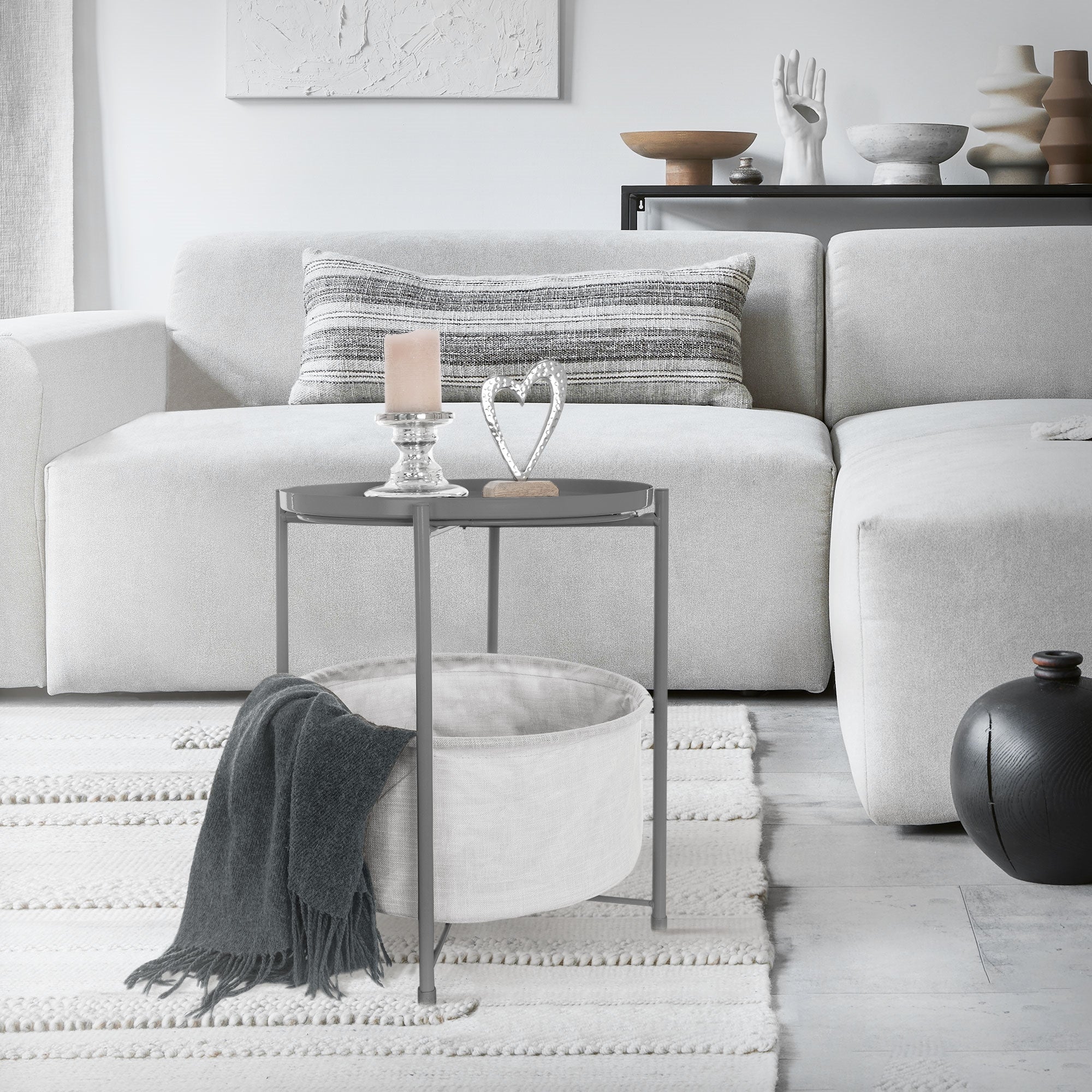 Wohnzimmer mit grauem Sofa, Tisch und Dekoration auf dem Tisch.