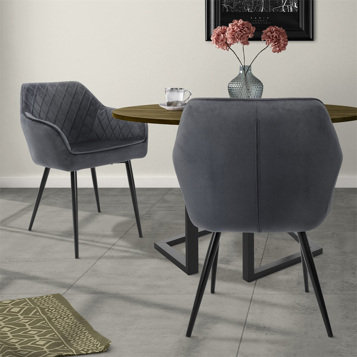Two gray chairs at a round table with a vase and flowers.