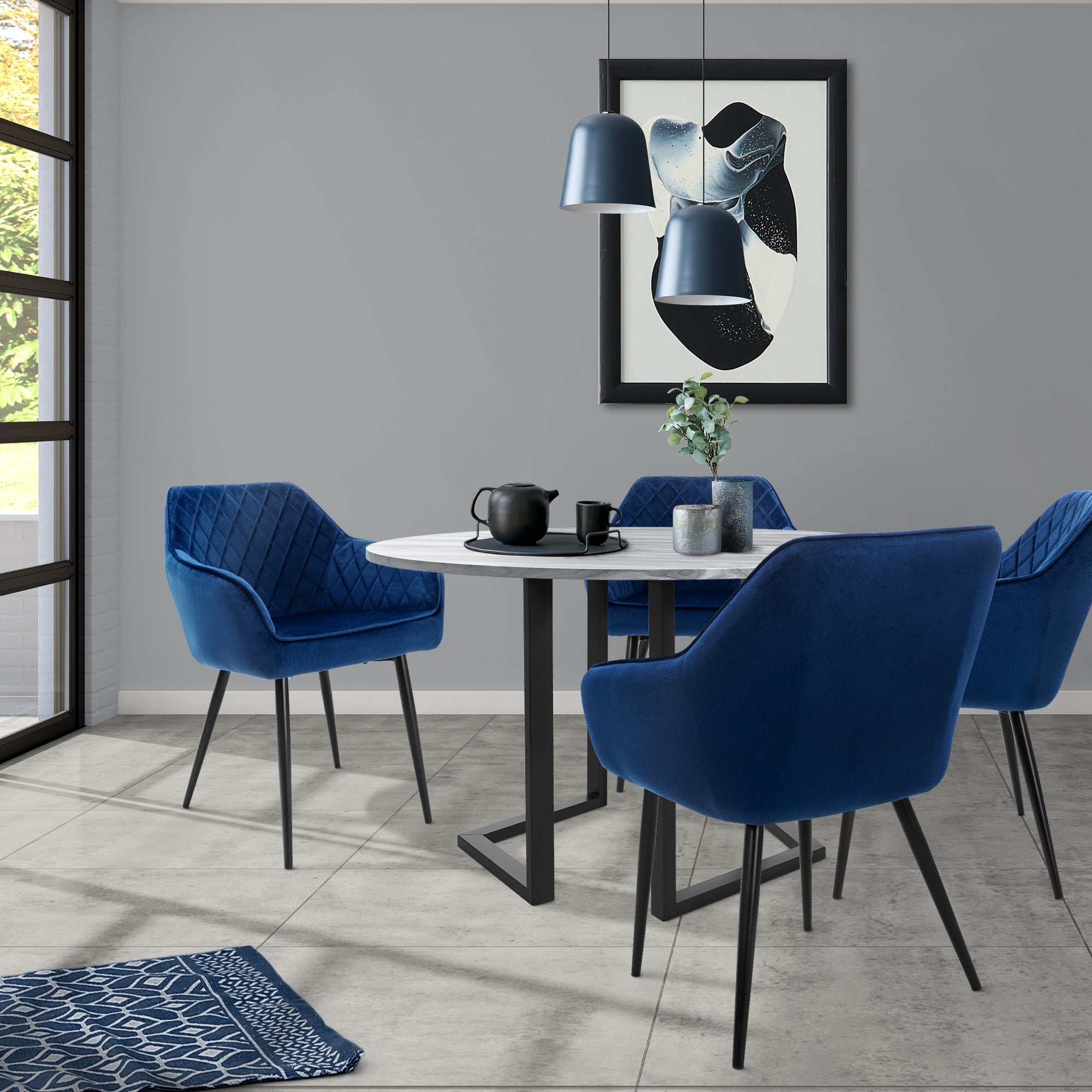 Ein moderner Essbereich mit runden Tisch und blauen Stühlen vor einem Fenster.