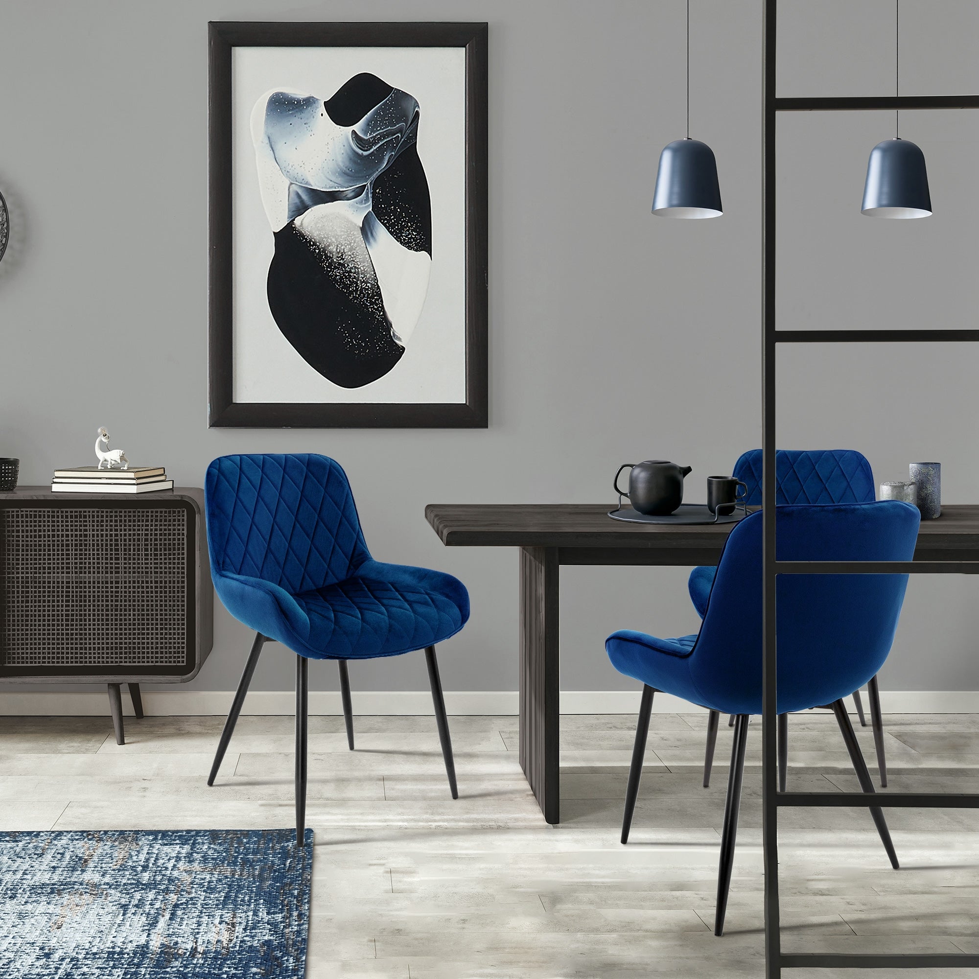 Blick auf einen Tisch mit zwei blauen Stühlen und einem Kunstwerk an der Wand.
