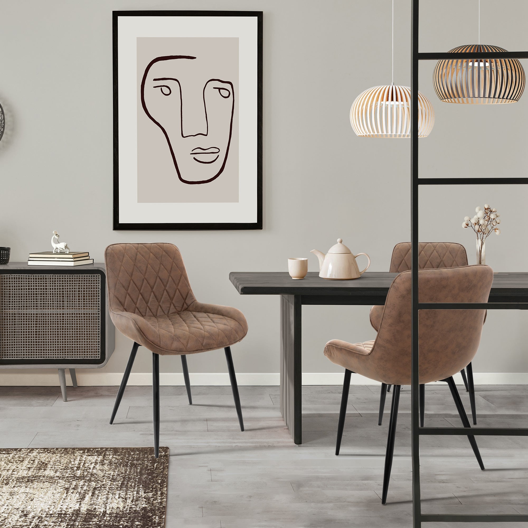 Ruokailuhuone ruskeilla tuoleilla, pöydällä, teekannulla ja seinätaiteella.