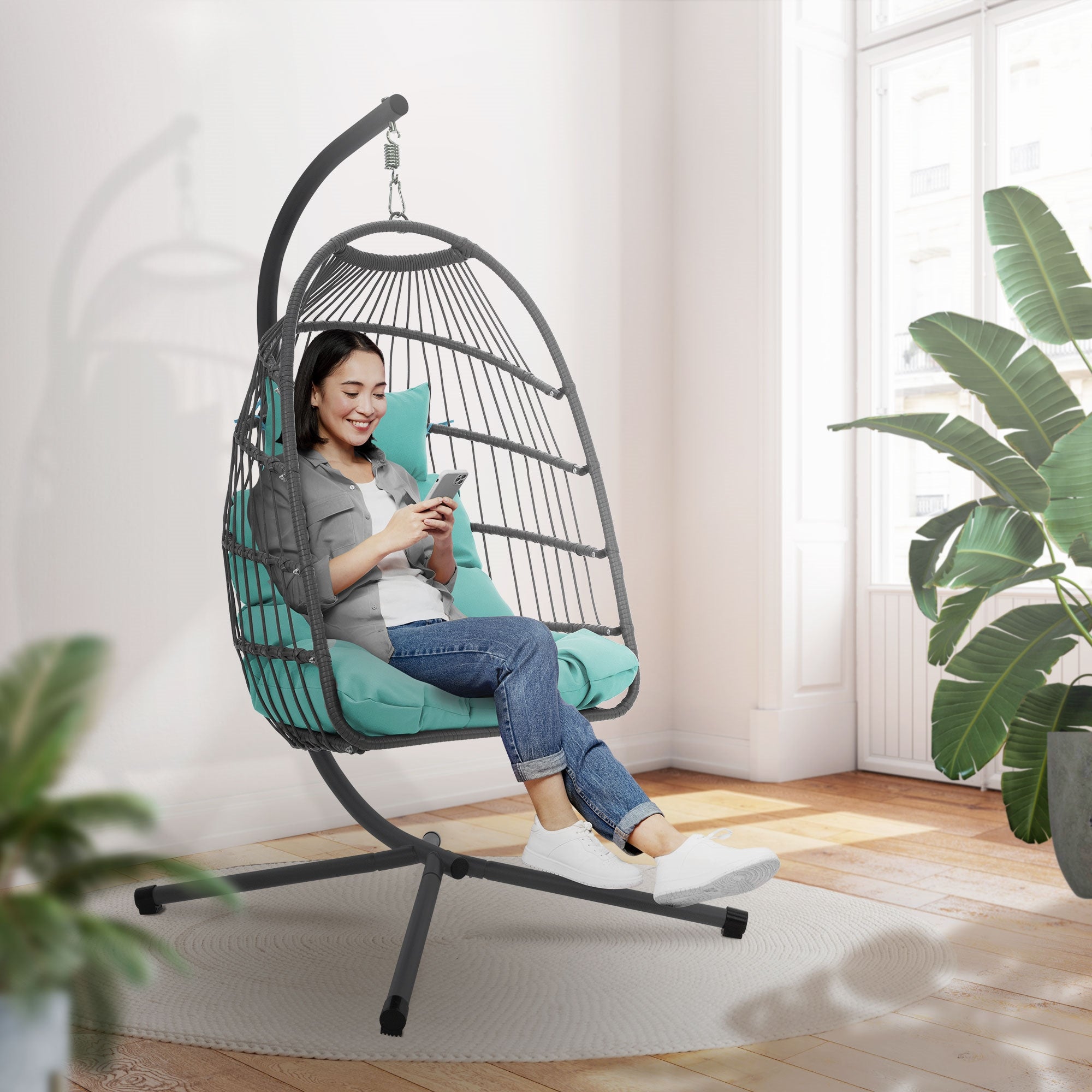 Femme assise dans une chaise suspendue utilisant un smartphone.