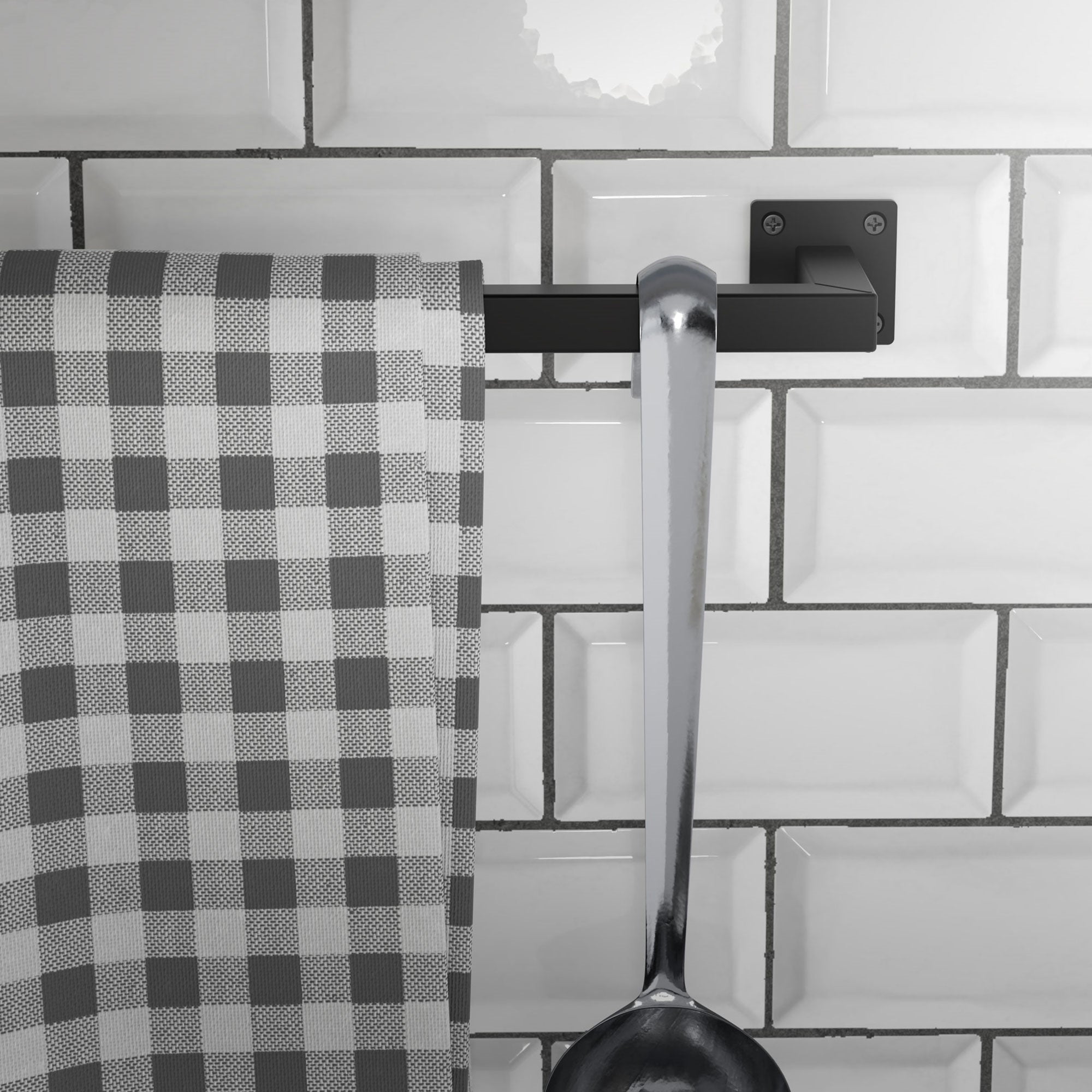 Et køkkenhåndklæde hænger på en sort holder ved siden af en stor ske.