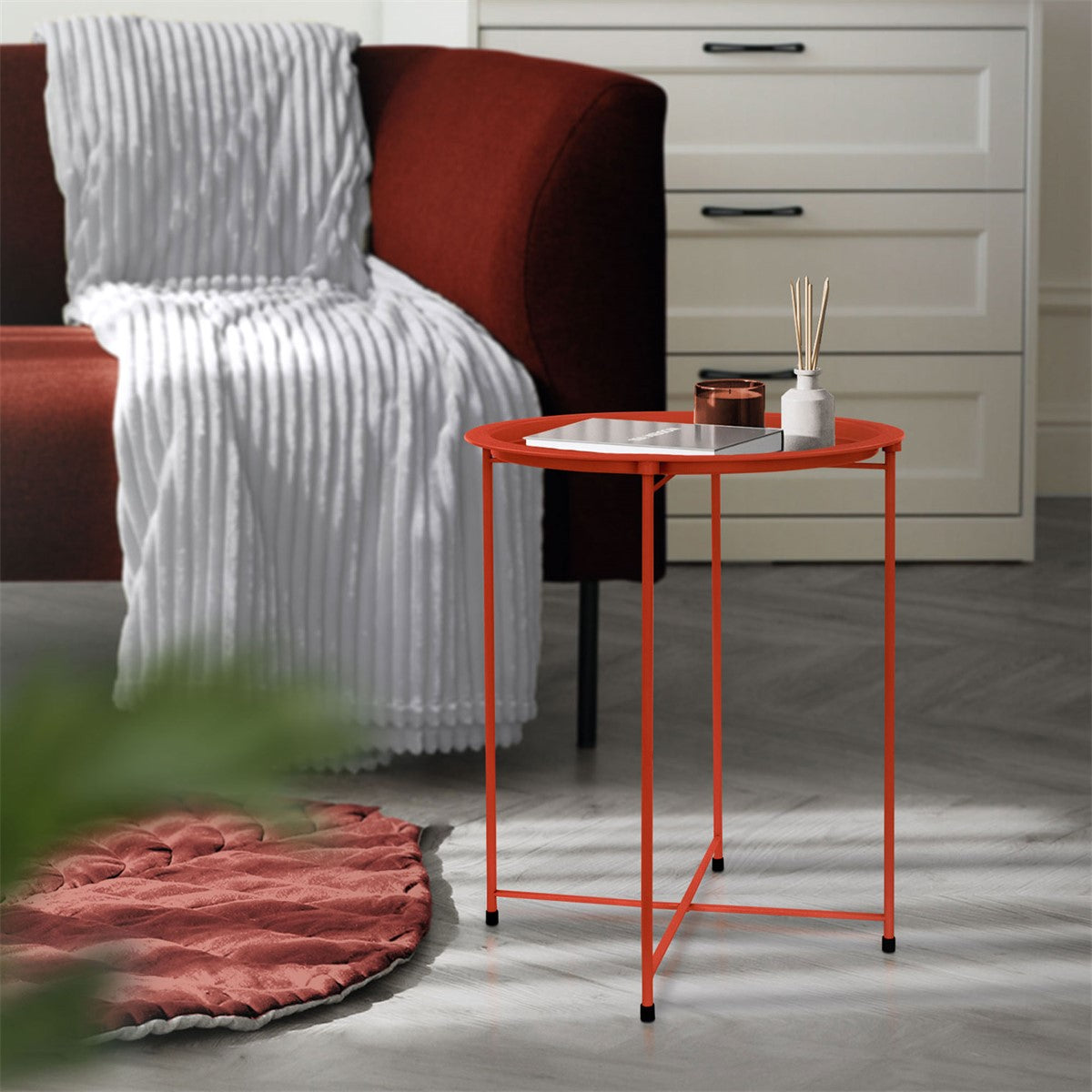 Ein orangefarbener Tisch mit einer weißen Platte, neben einem roten Sessel.