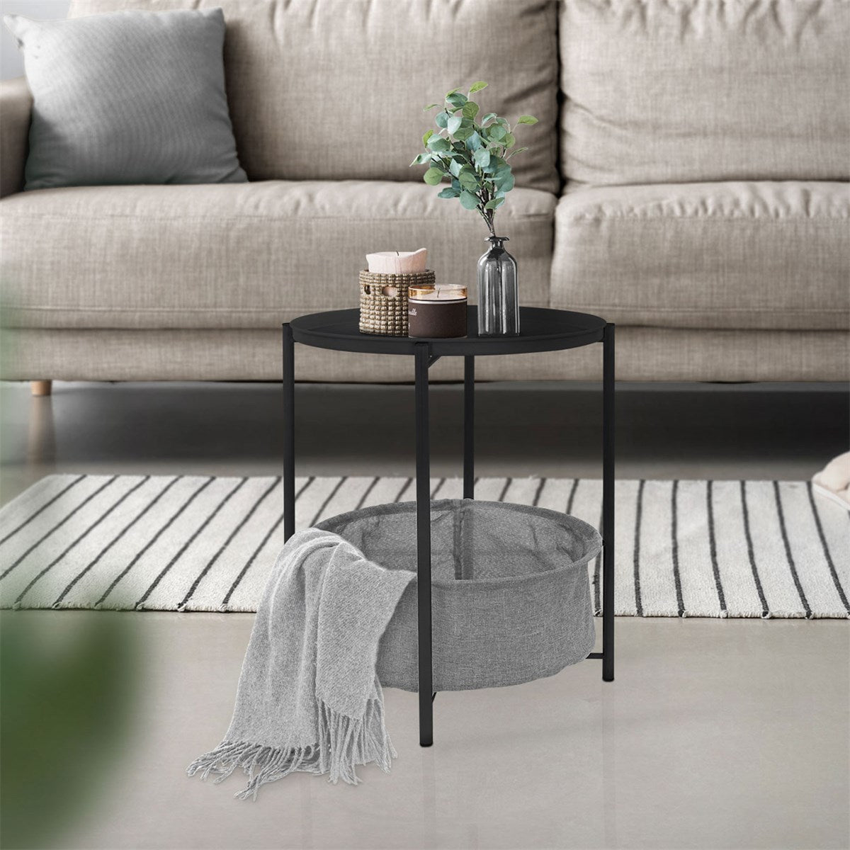 A round table with a black frame and gray basket, decorated with a plant.