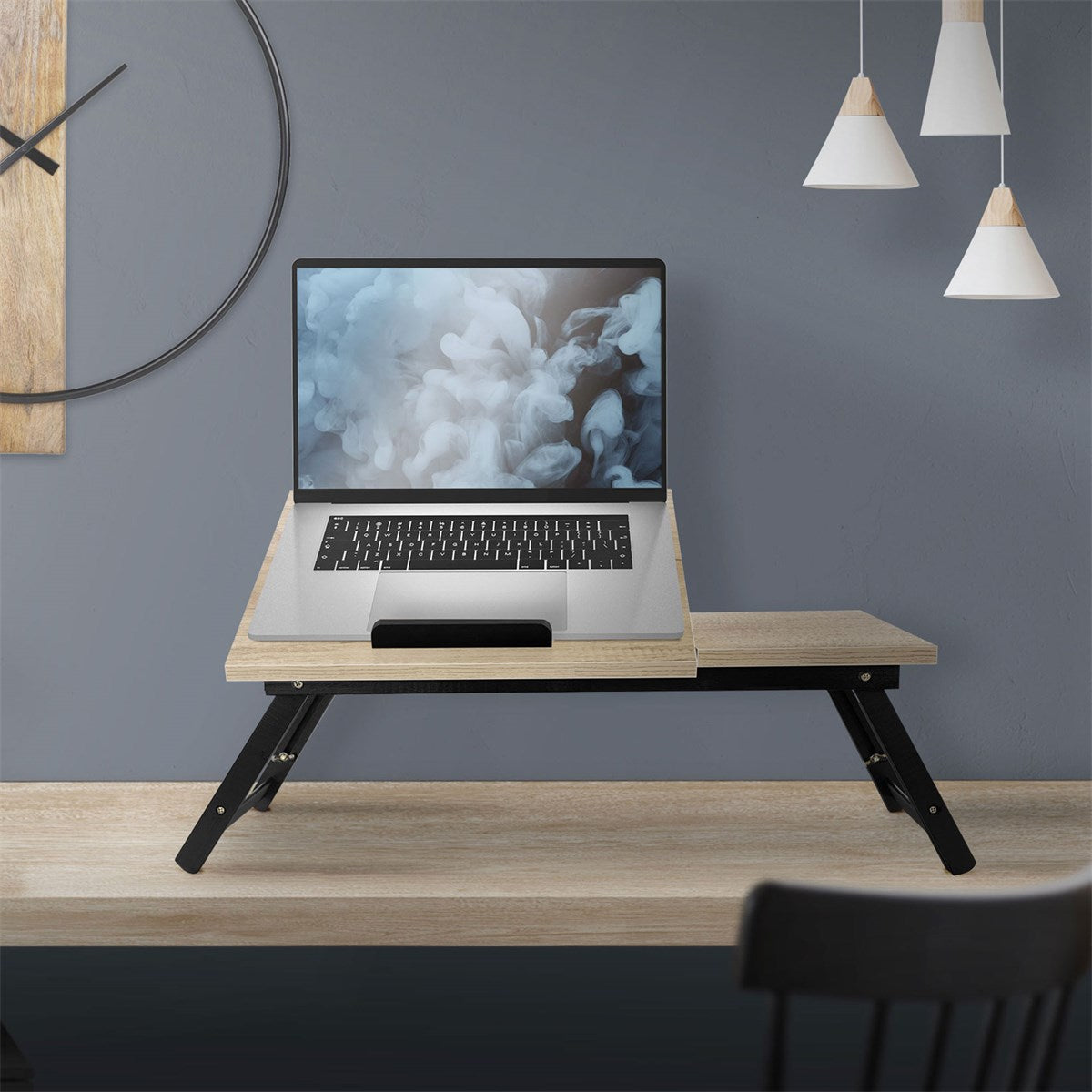 Un ordinateur portable sur une table pliante devant un mur gris.