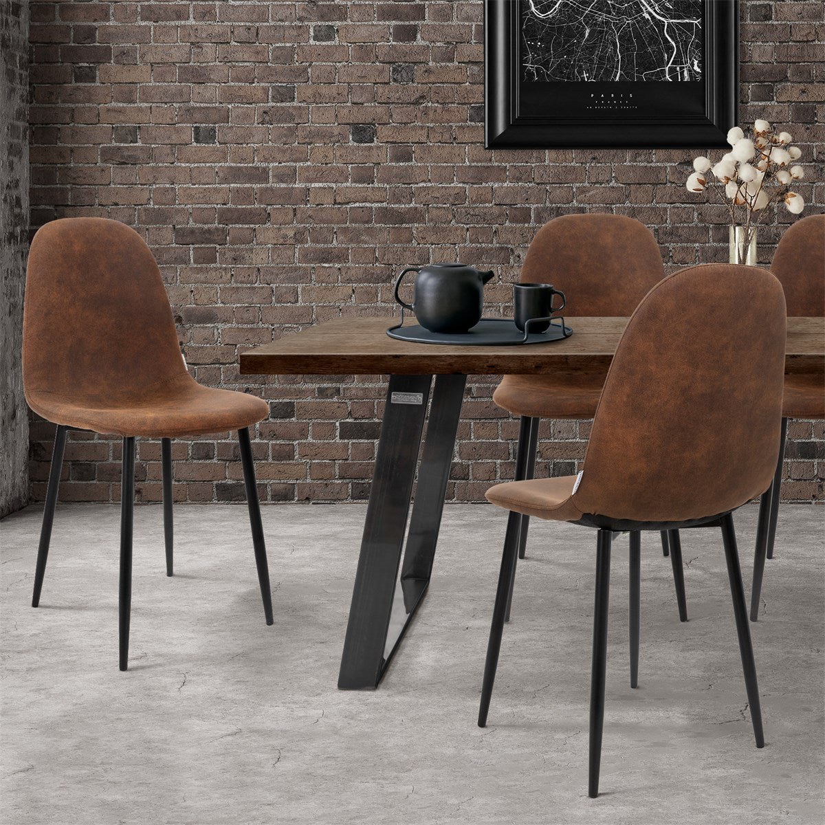 A dining room with a wooden table and four brown chairs in front of a brick wall.