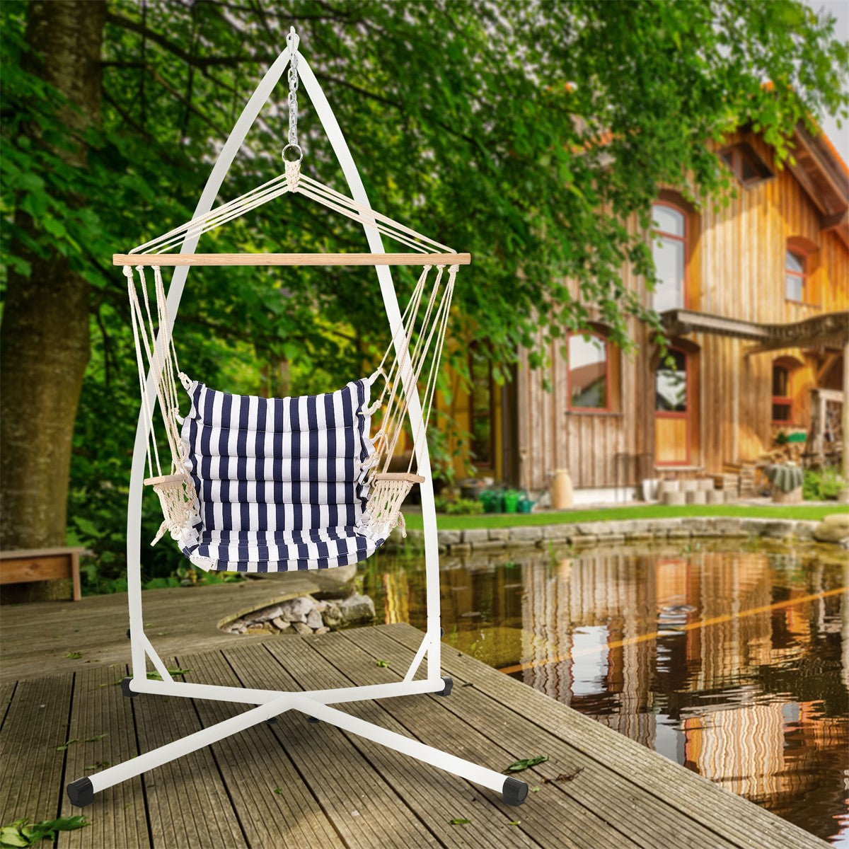 Hängesessel mit gestreiftem Bezug vor einem Holzhaus und Teich.