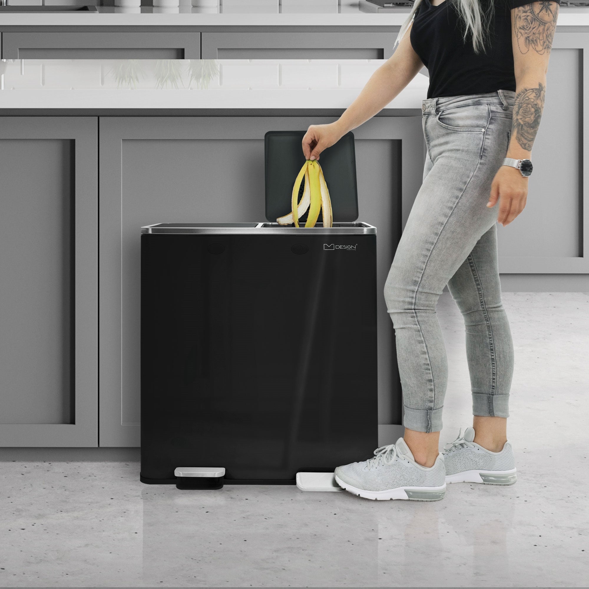 Person mit langen Haaren wirft eine Banane in einen schwarzen Mülleimer.