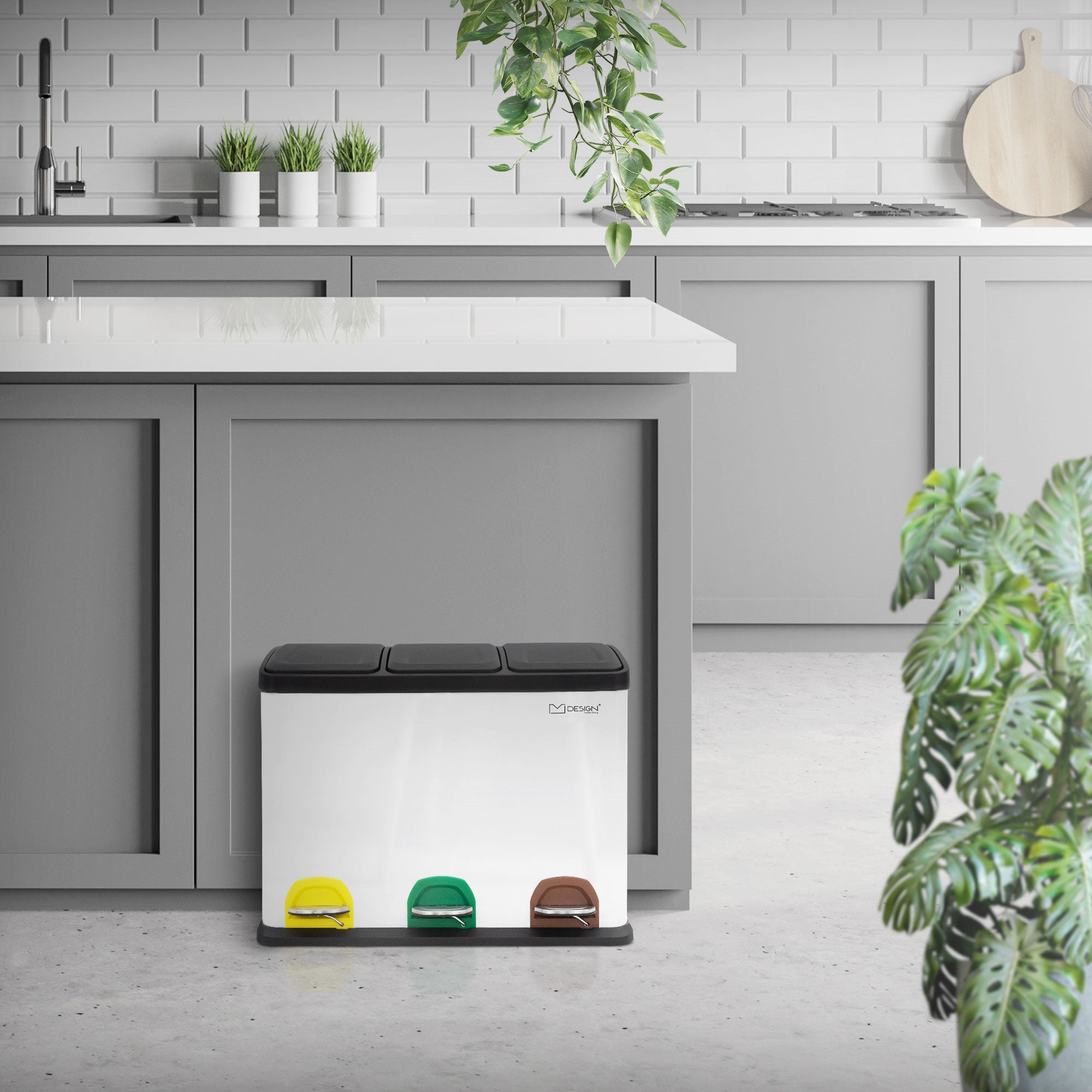 Mülltrennsystem in einer modernen Küche, neben einer Kücheninsel, Pflanzen im Hintergrund.