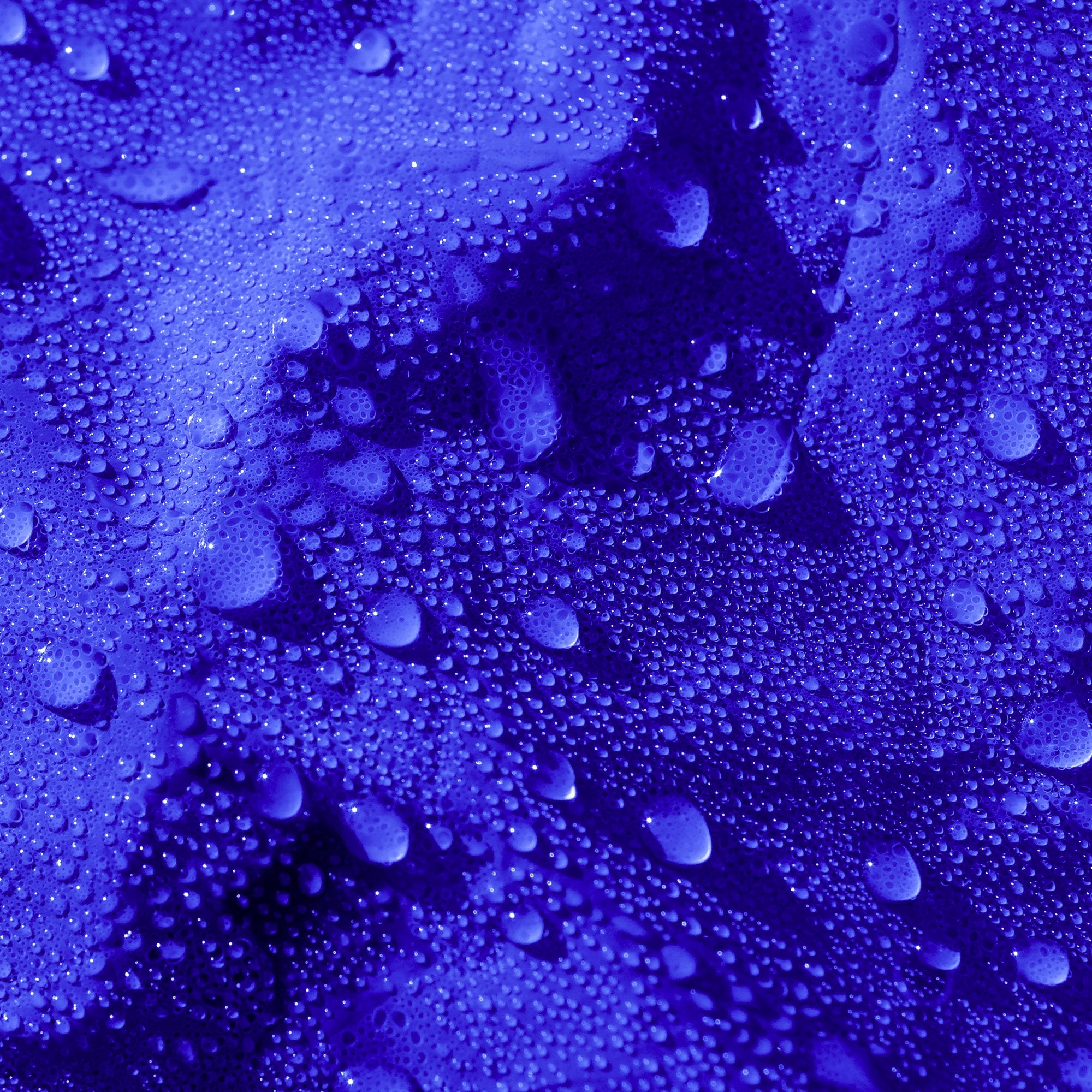 Nahaufnahme einer blauen Plane mit Wassertropfen auf der Oberfläche.
