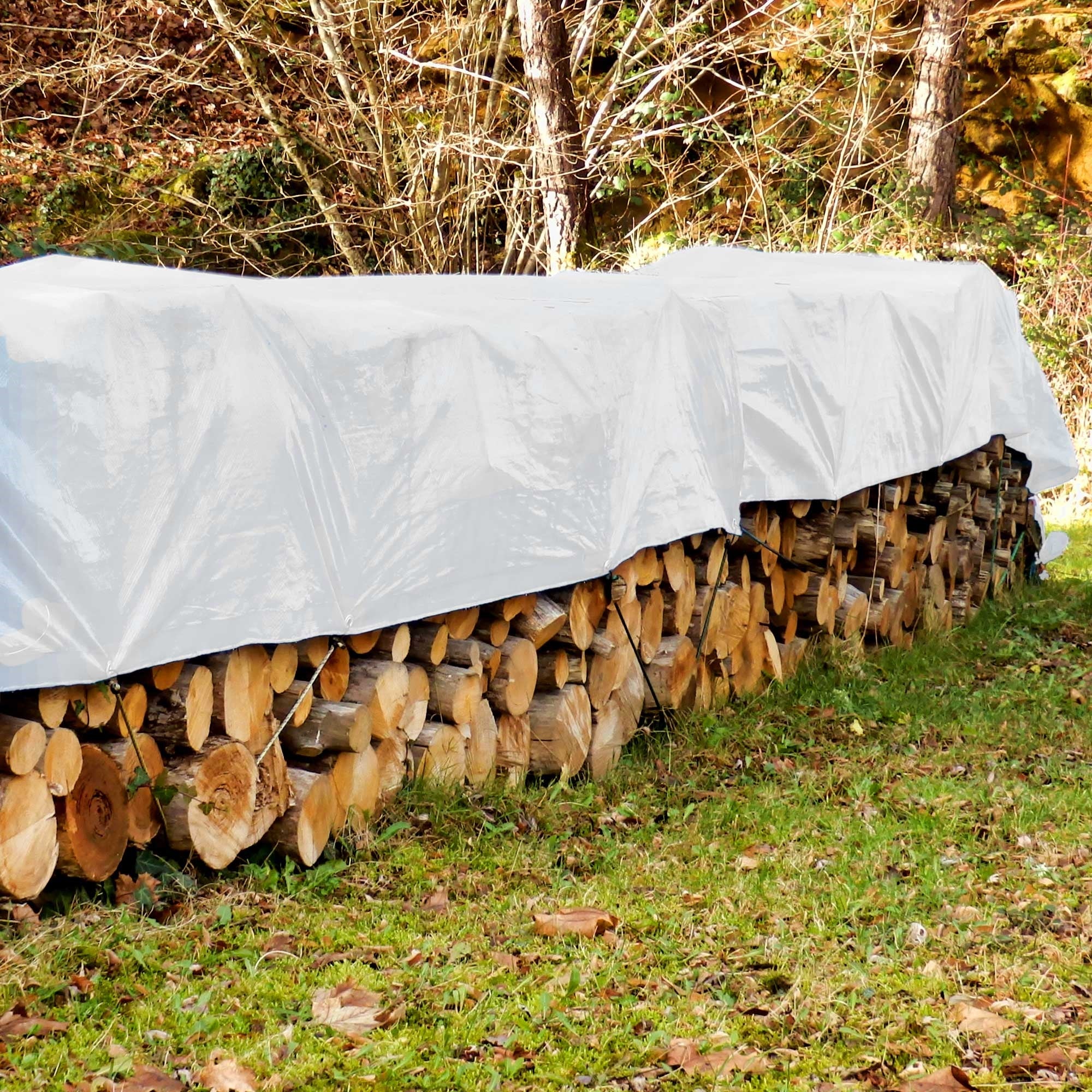 Un mucchio di ceppi di legno, coperto con un telo bianco all'aperto.