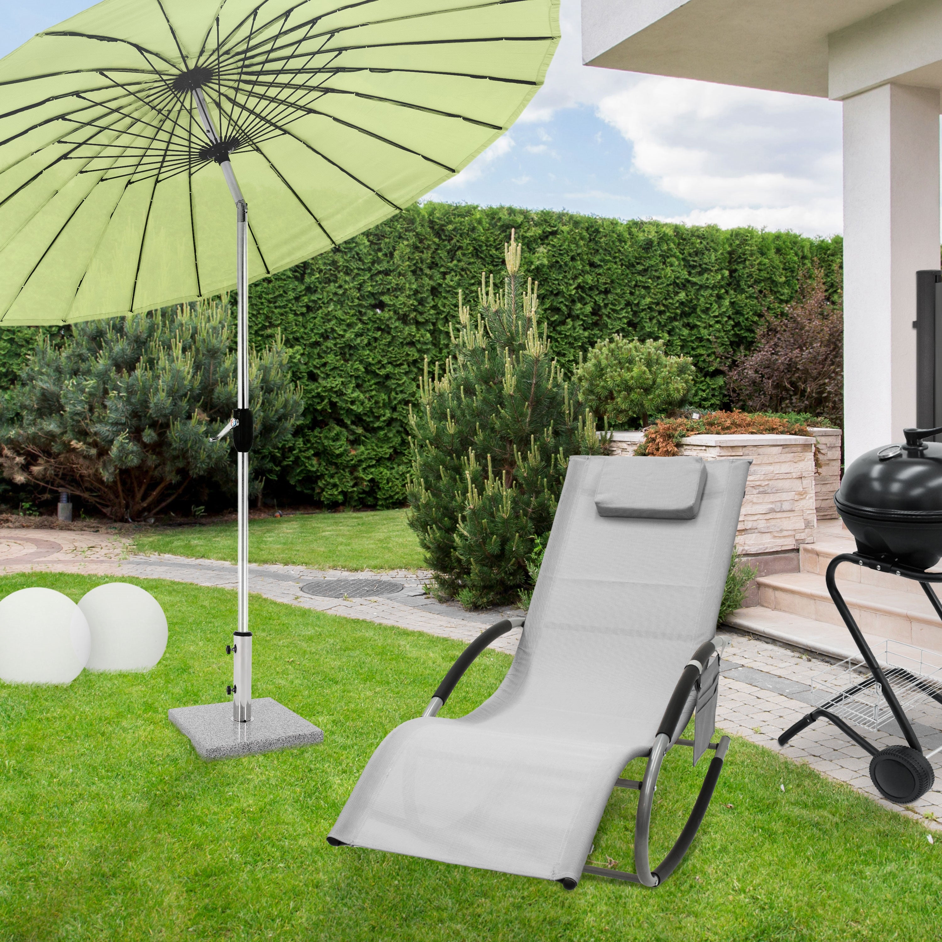 Ein Garten mit einem Liegestuhl, einem Sonnenschirm und einem Grill.