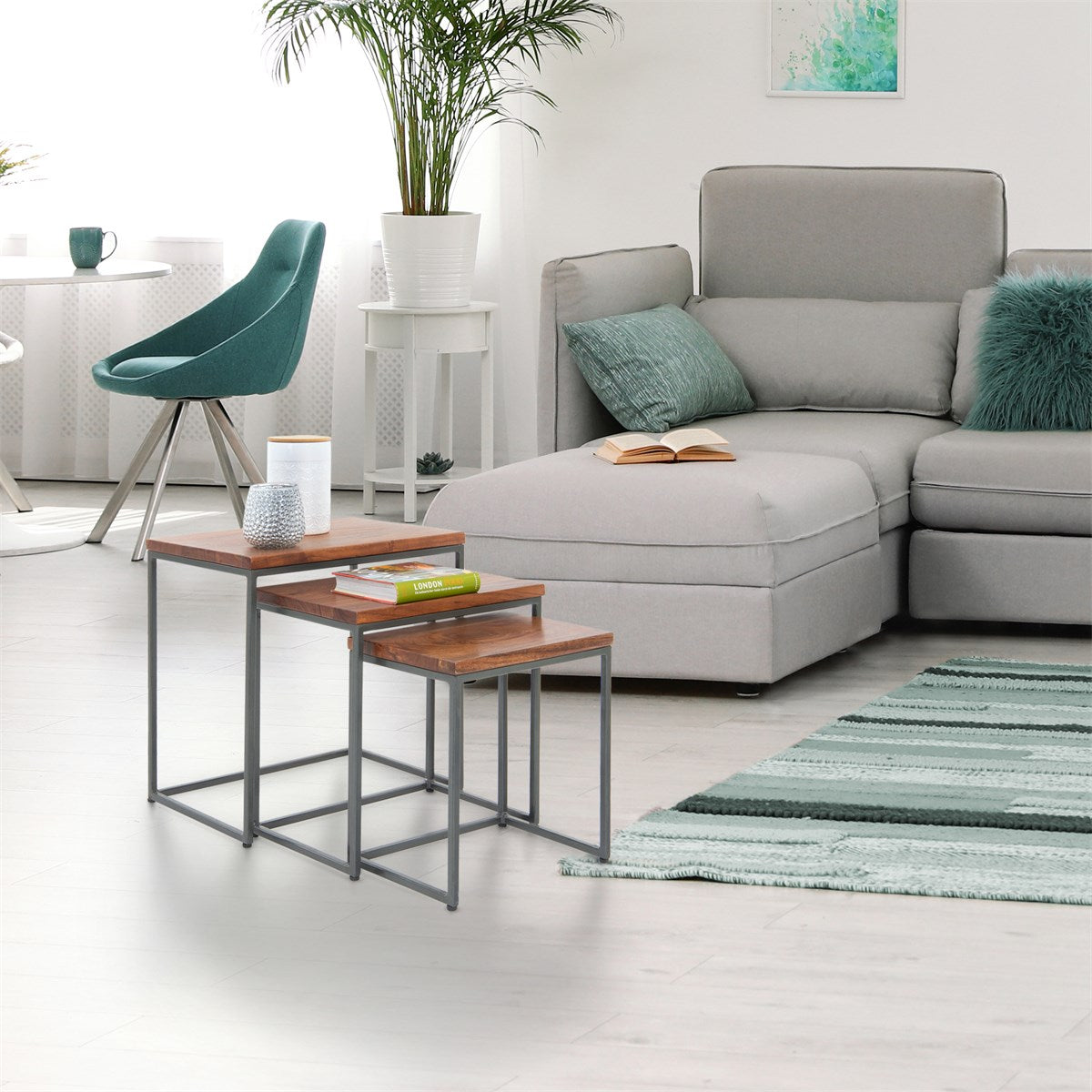Woonkamer met twee bijzettafels, een bank en een vloerkleed, met planten op de achtergrond.