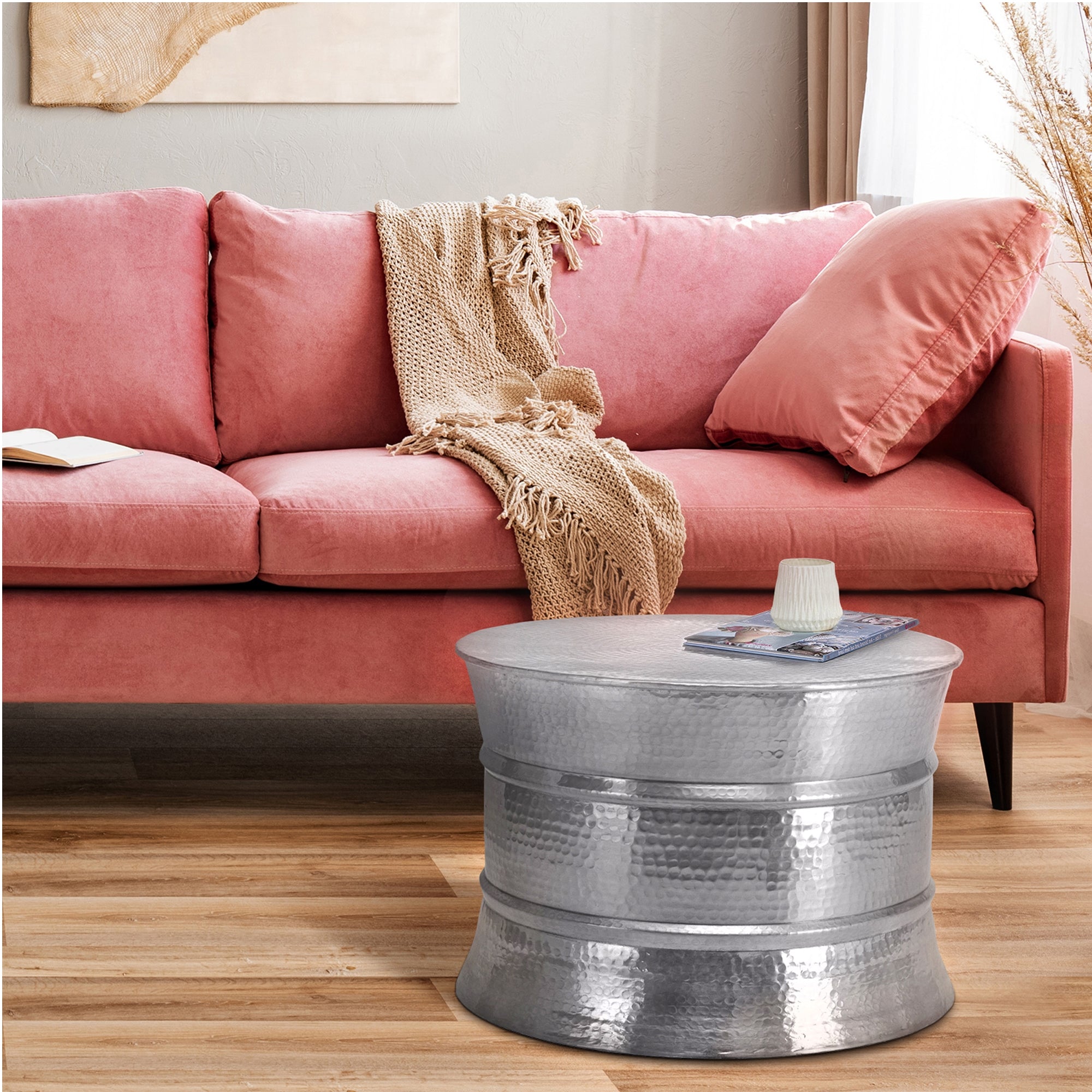 Wohnzimmer mit rosa Sofa und silbernem Tisch.