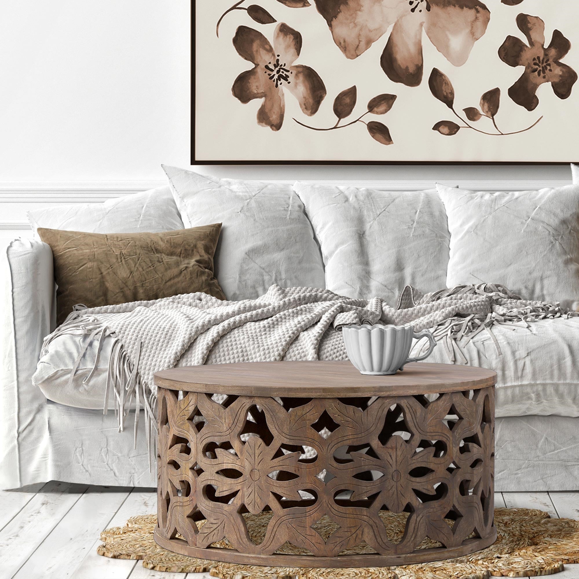 Beige Couch mit Decke und runder Tisch mit Blumenmuster im Hintergrund.