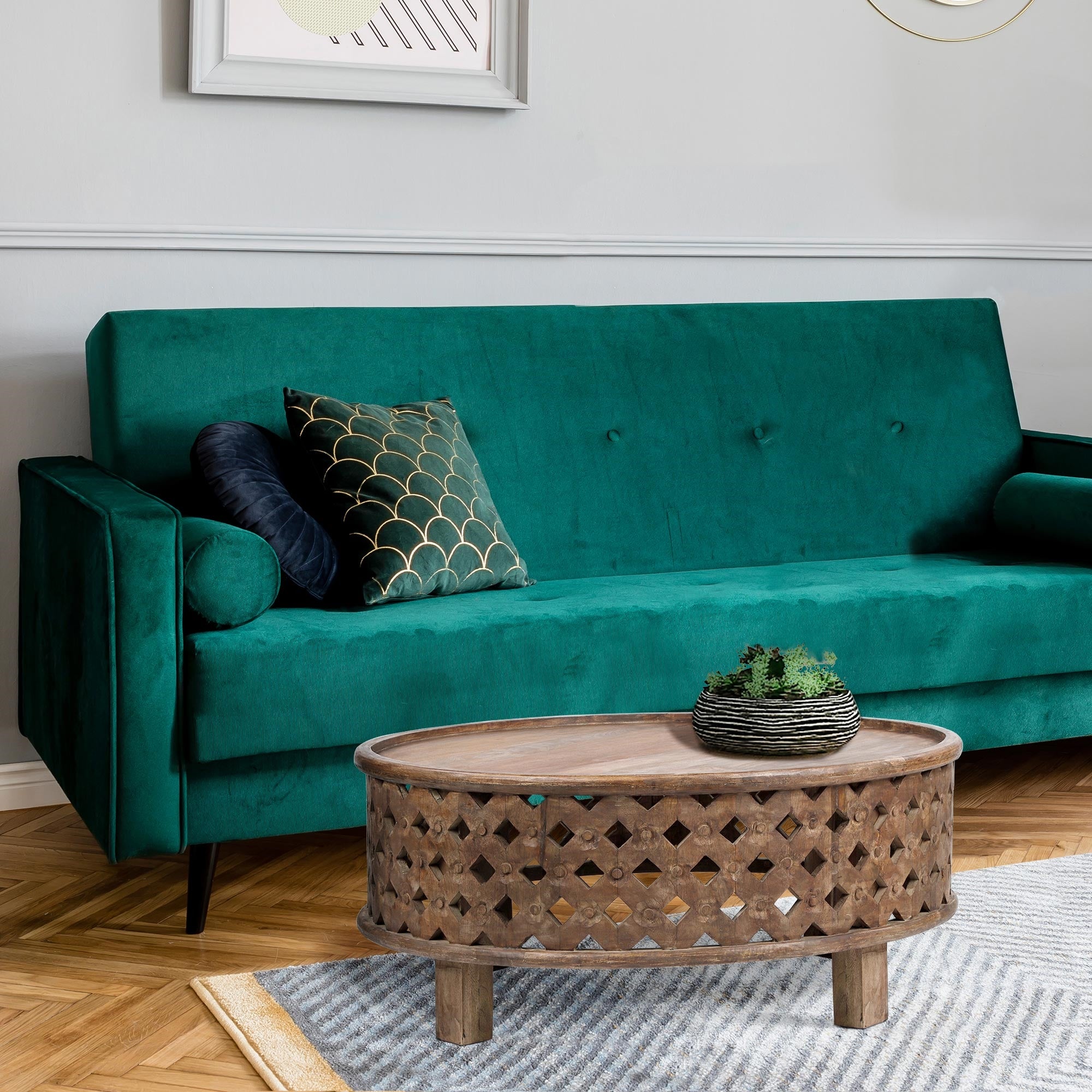 Sofá verde con cojines y una mesa redonda de madera en la sala de estar.
