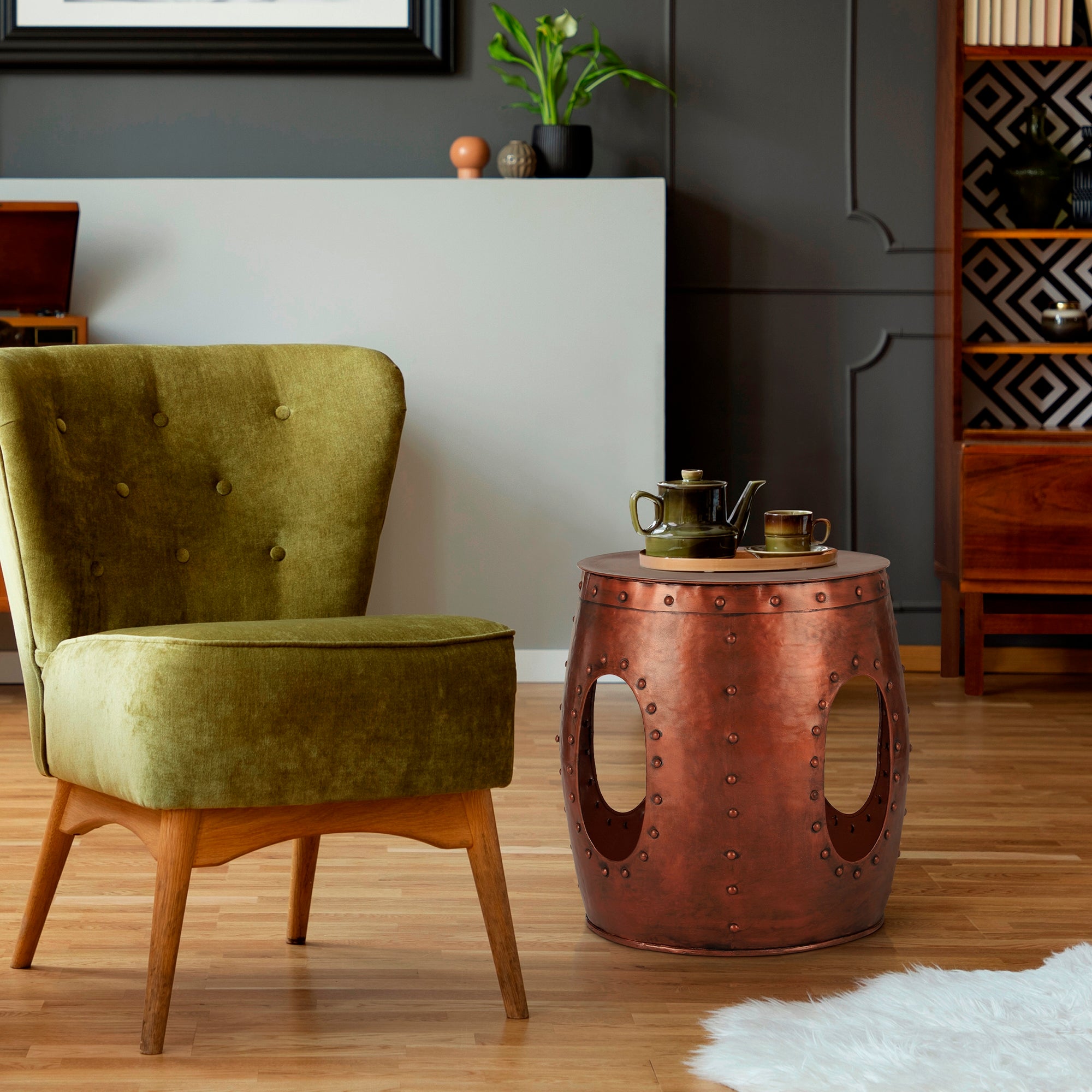 Poltrona verde con gambe in legno e tavolino color rame in una stanza elegante.