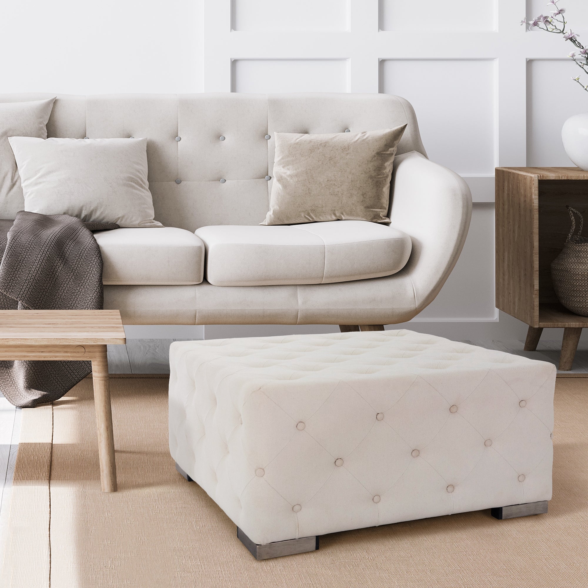 Beige Couch mit Kissen und einem quadratischen Hocker im Raum.