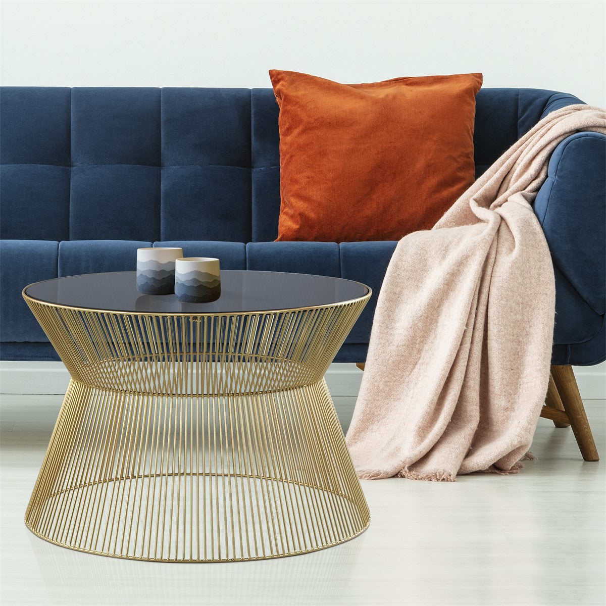 Blauer Sofa mit orangefarbener Kissen, einem runden Tisch und einer Decke.